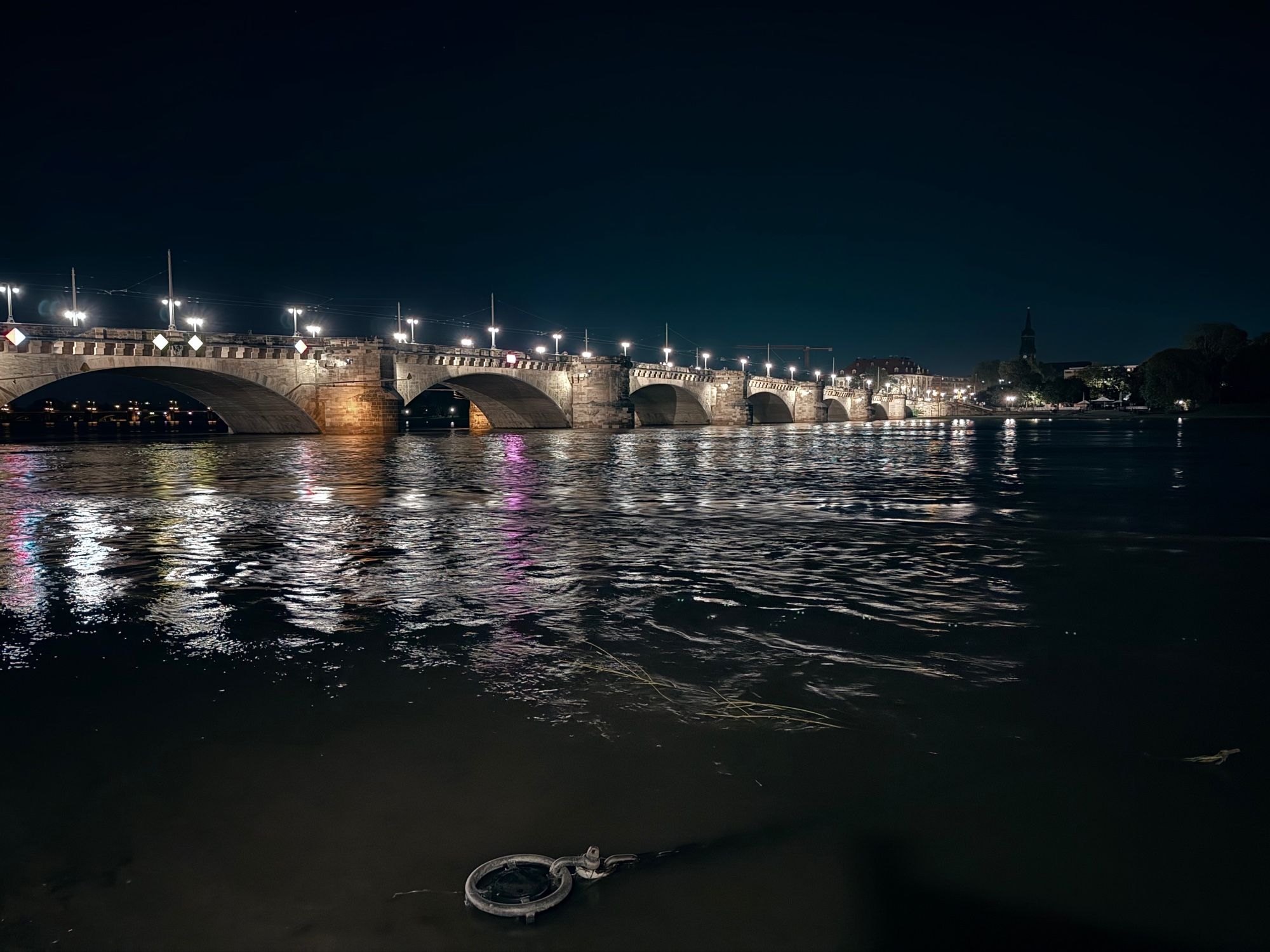 Blick auf die Augustusbrücke direkt am Wasser, Abendstimmung mit Straßenbeleuchtung