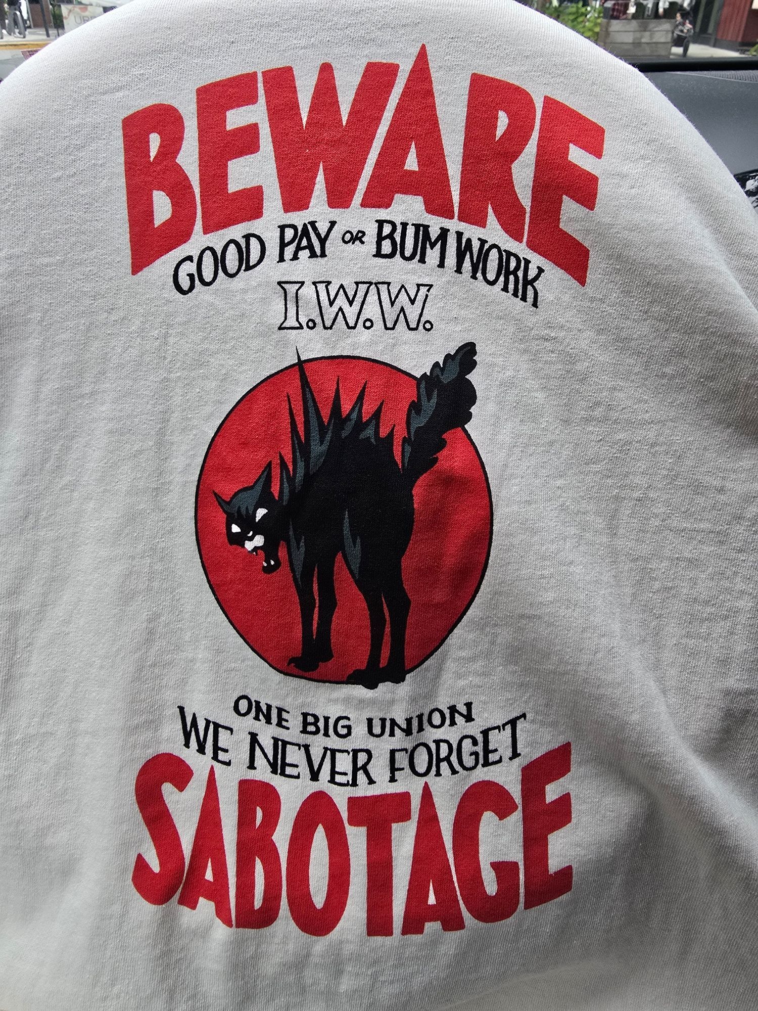 A t-shirt with the IWW cat and the words "beware, good pay or bum work, I.W.W., one big union, we never forget, sabotage"