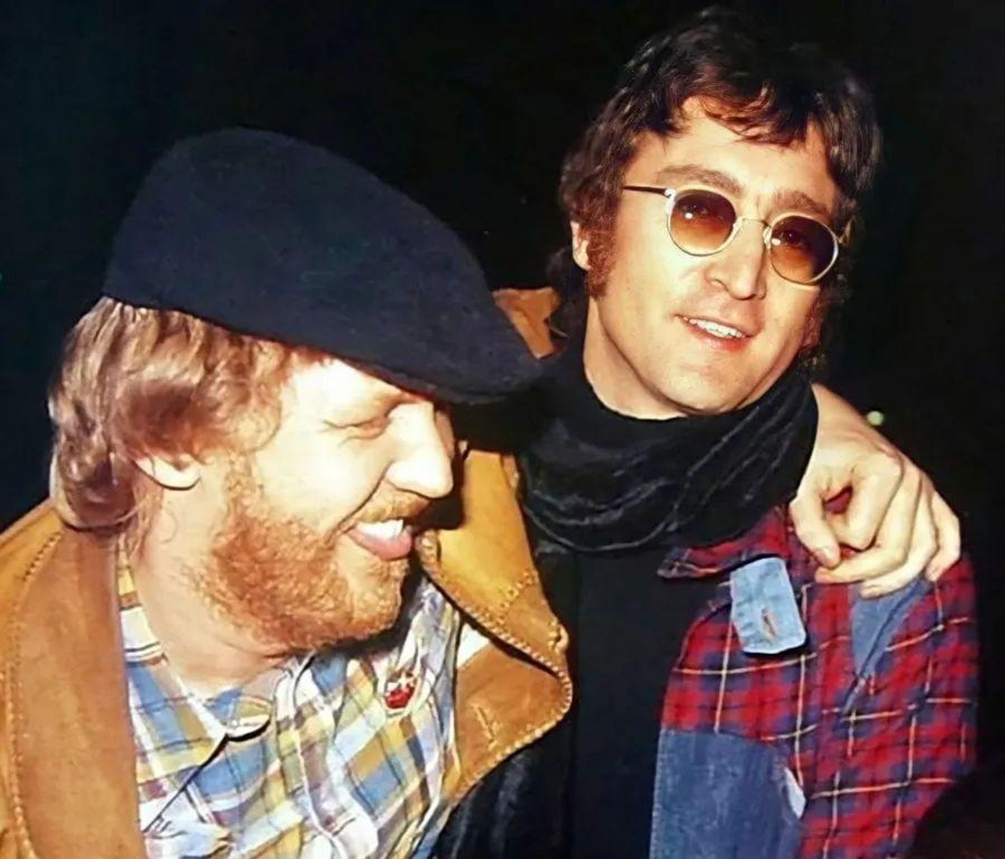 Harry Nilsson, pelirrojo, con barba, camisa a cuadros, chaqueta de ante marrón y gorra negra, abraza a un Jonh Lennon que luce camisa a cuadros rojos, gafas de sol y un pañuelo al cuello. Se les ve muy contentos, lo que es un eufemismo de que van algo pasados de rosca. Rolling Stone.