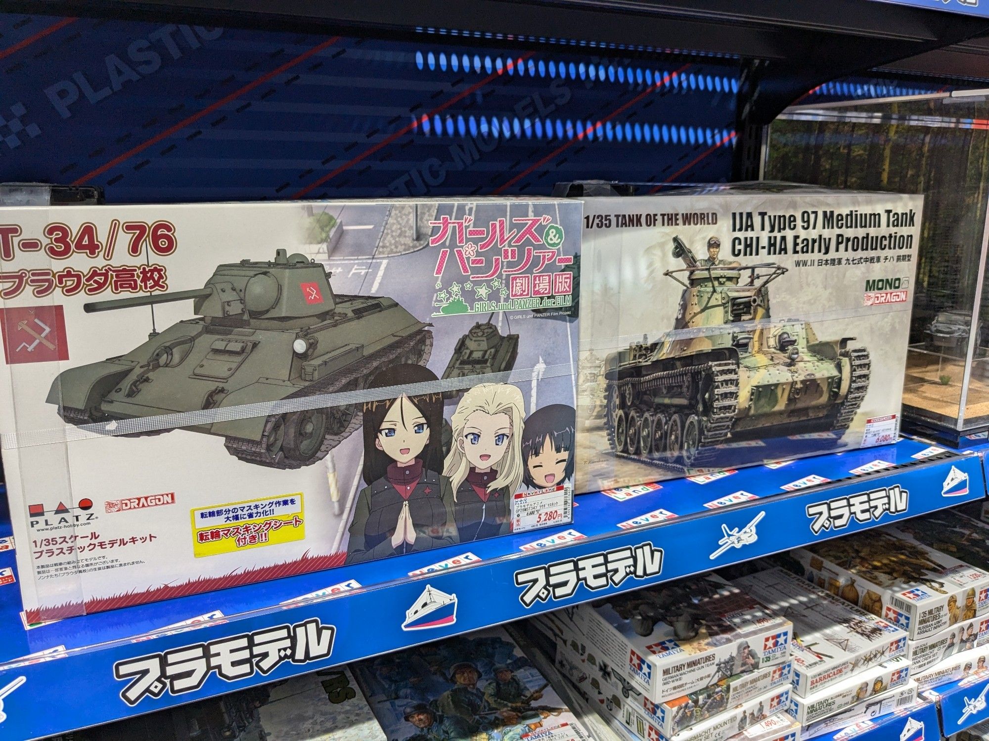 2 model tank kits. The left one has anime characters from girls und panzer on it, the right one has a detailed military man on it.