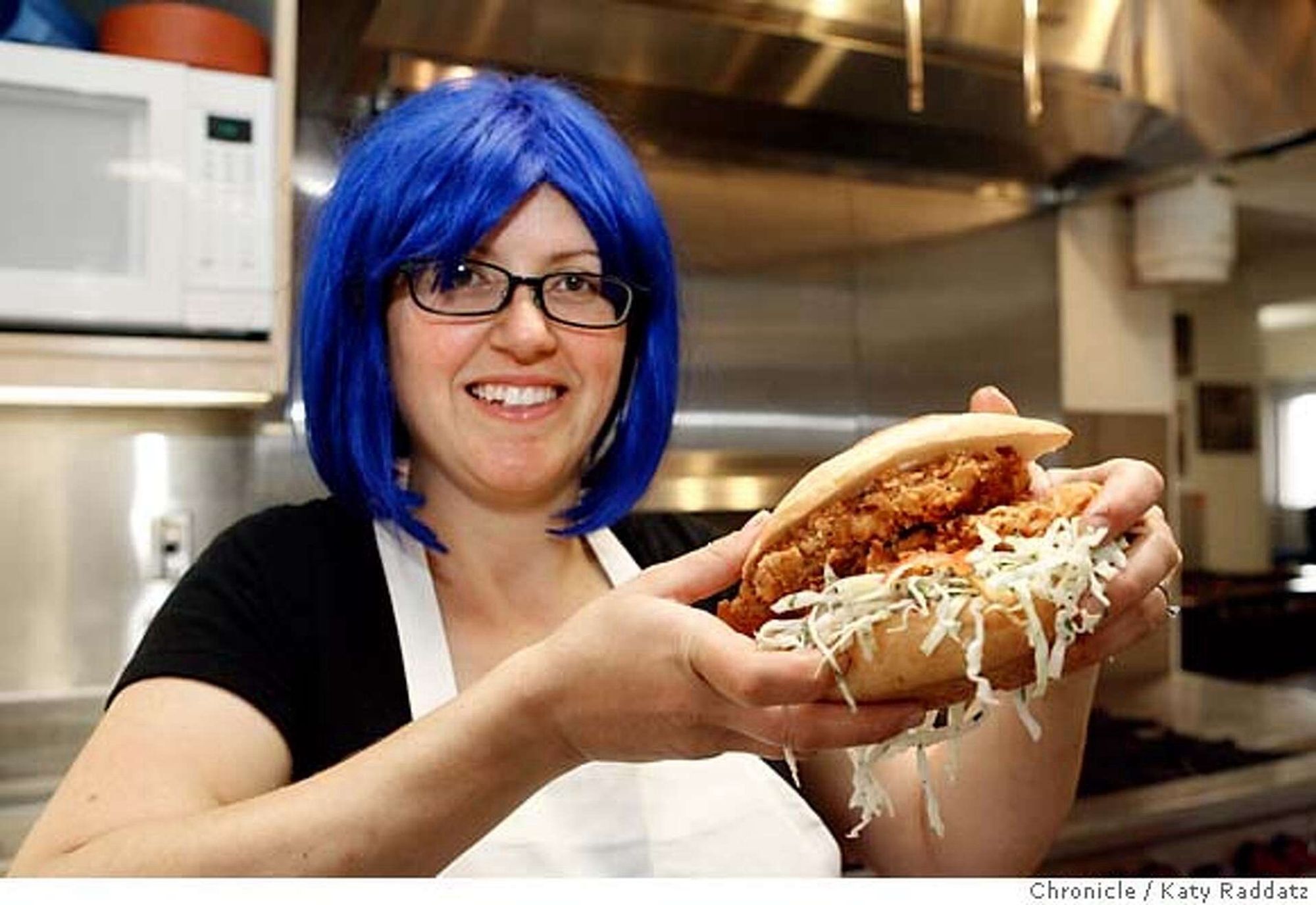 A person with jewel blue hair and a white apron holding the best goddamn chicken sandwich ever. Bakesale Betty’s in Oakland CA. Worth the trip from anywhere really