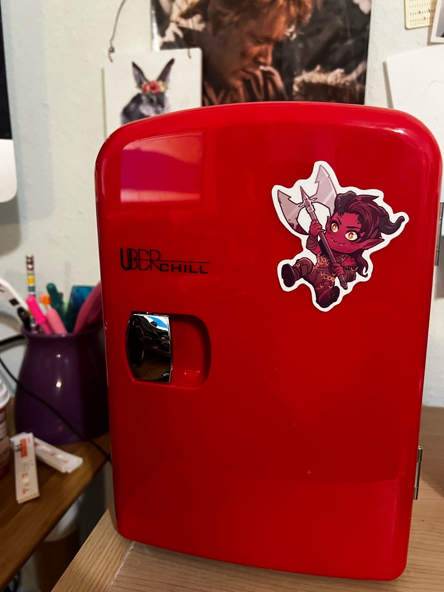 Very small red fridge with a sticker of Karlach from Baldur’s Gate on it