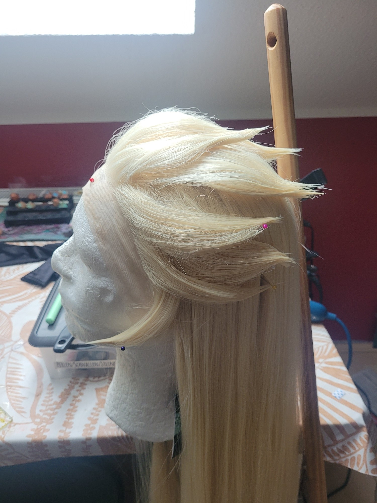 A styled wig on a wighead of the character lilith from Hazbin Hotel