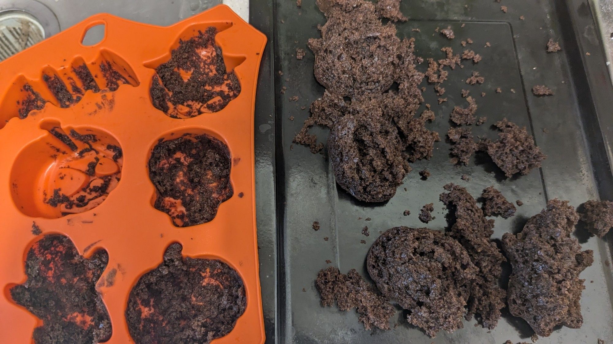 On the left, an orange cupcake mold with pumpkin, skull, bat, and ghost shapes filled with cake crumbs. On the right, piles of cake crumbs that were pulled from the molds