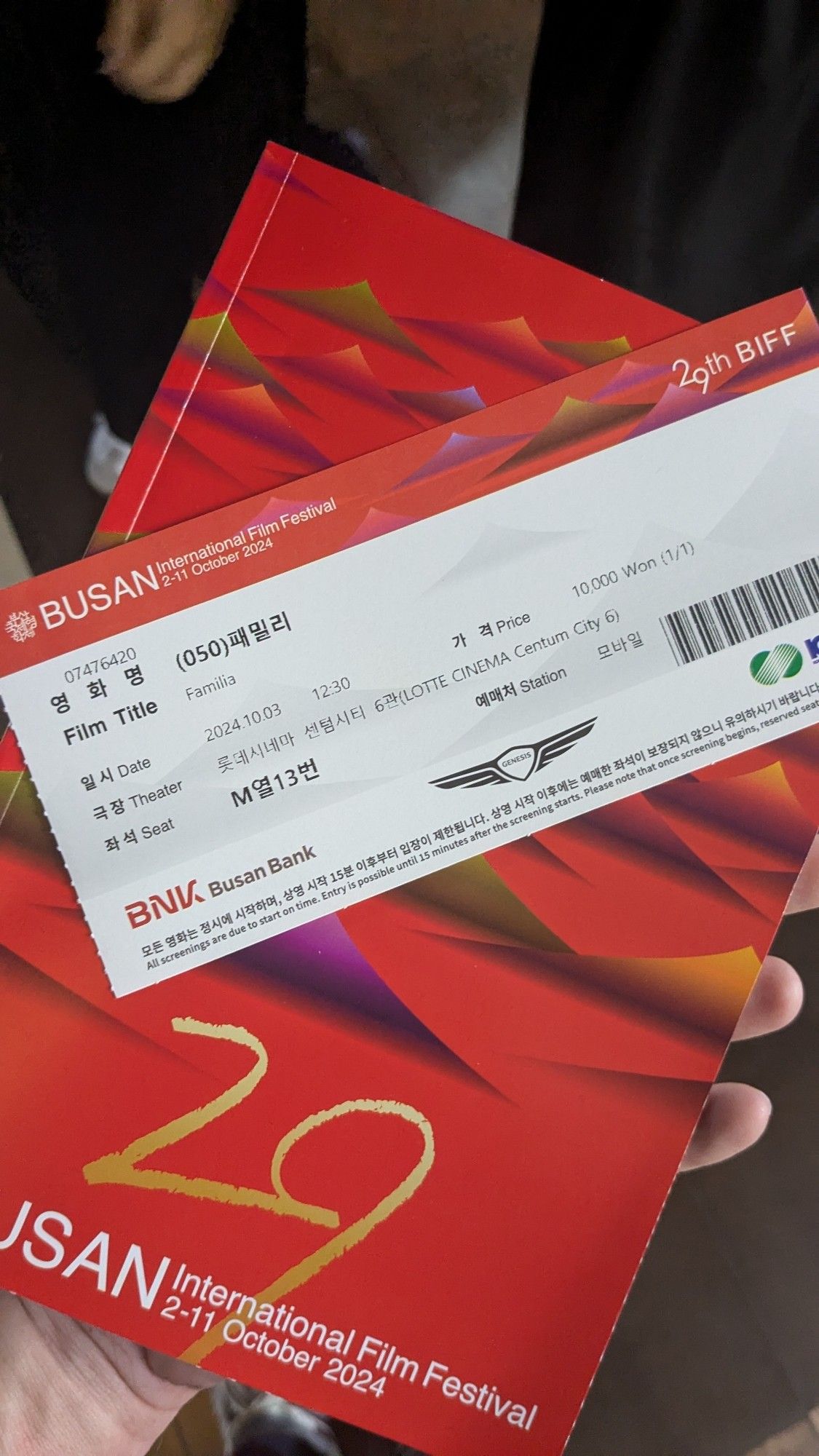 A ticket for a film at the Busan International Film Festival laying diagonally across a program guide for this year's festival