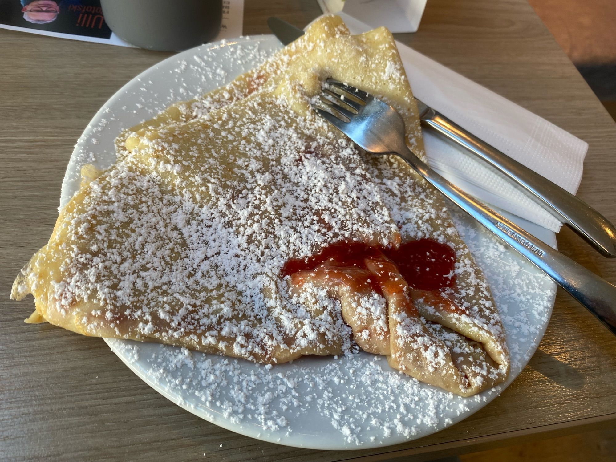 crepes with sugar powder and strawberry sauce.