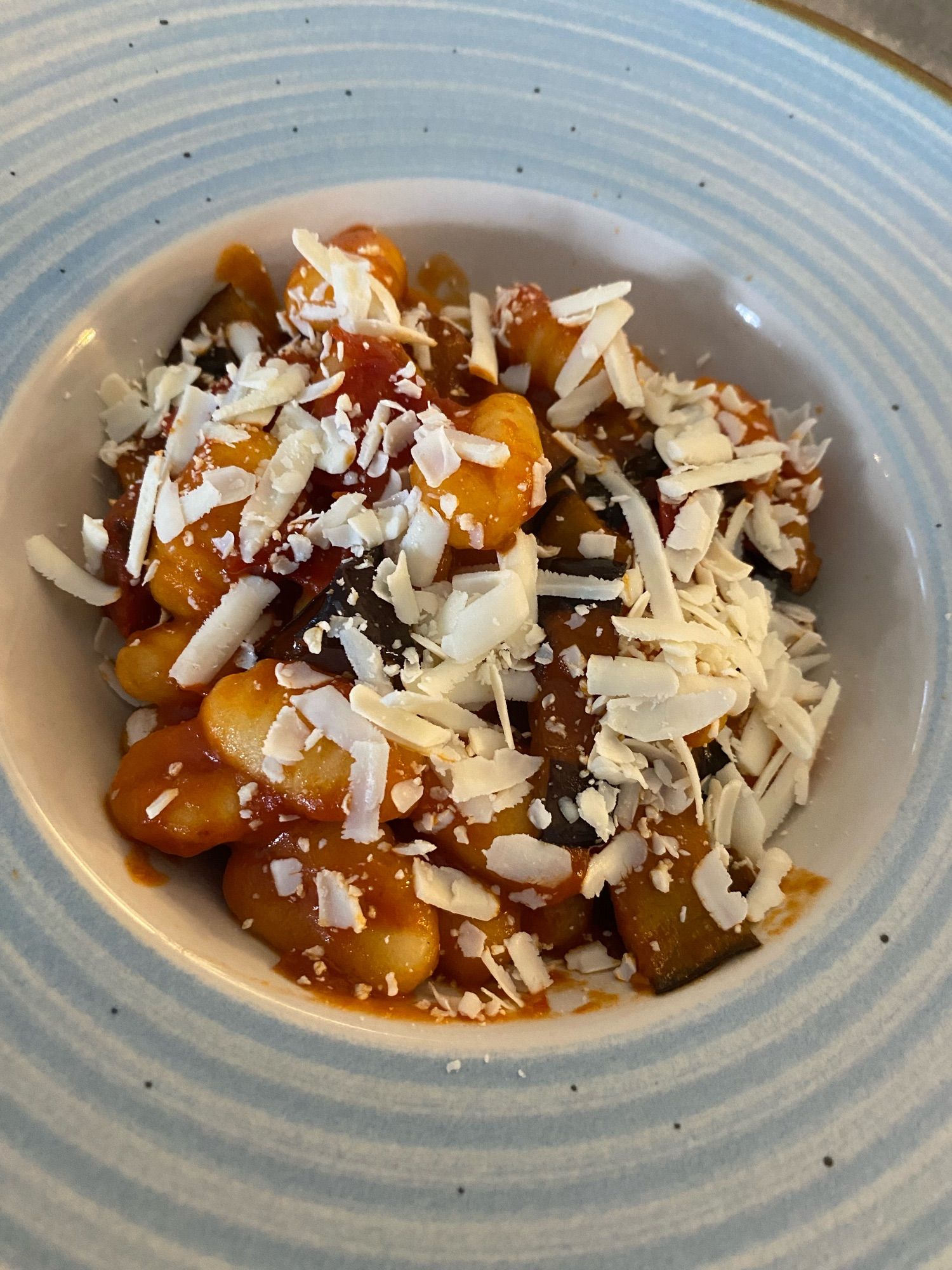 Gnocchi in tomato sauce and grilled aubergine slices. parmesan cheese on top.