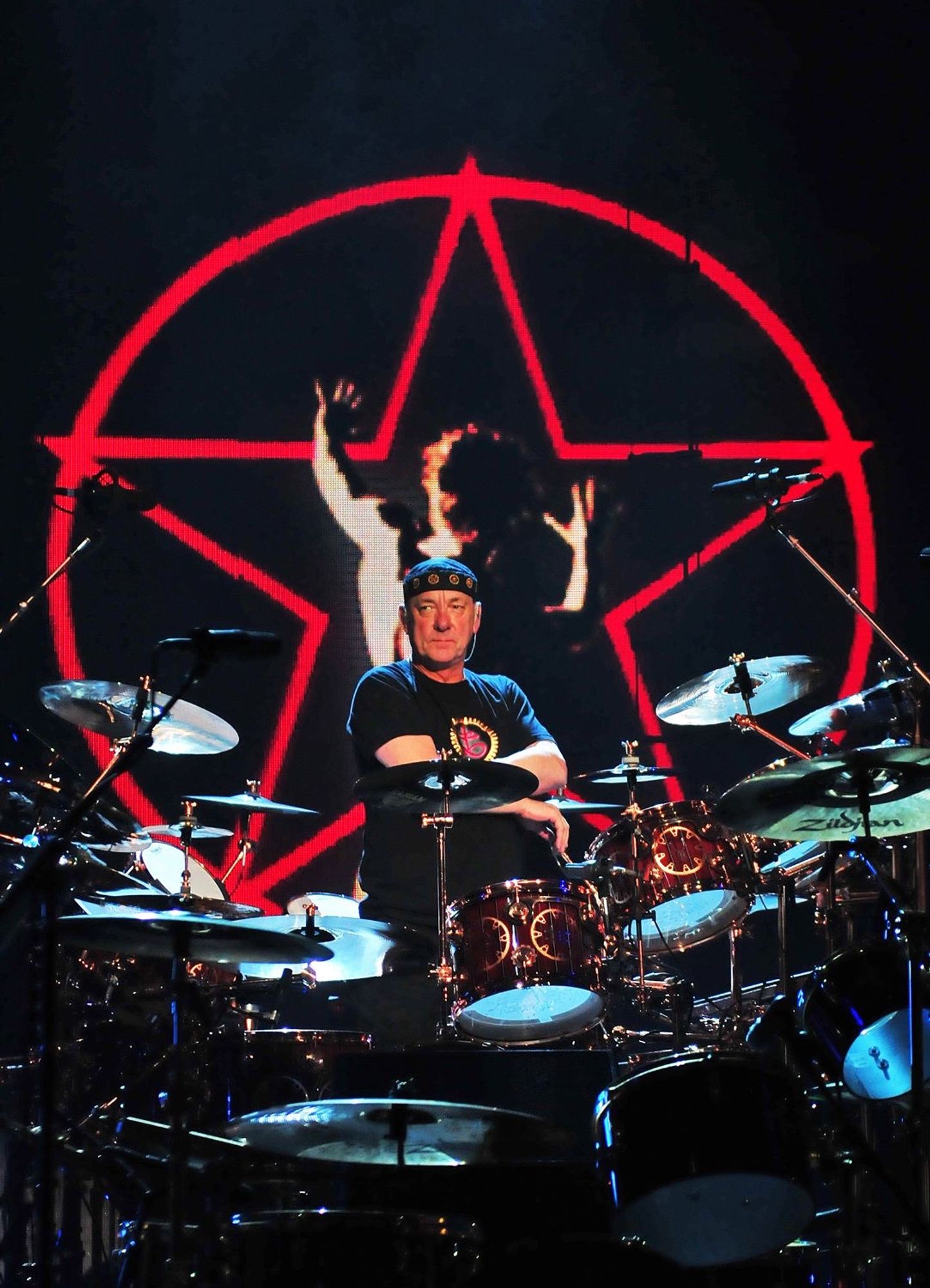 Neil Peart behind his drum kit - in front of the 2112 logo