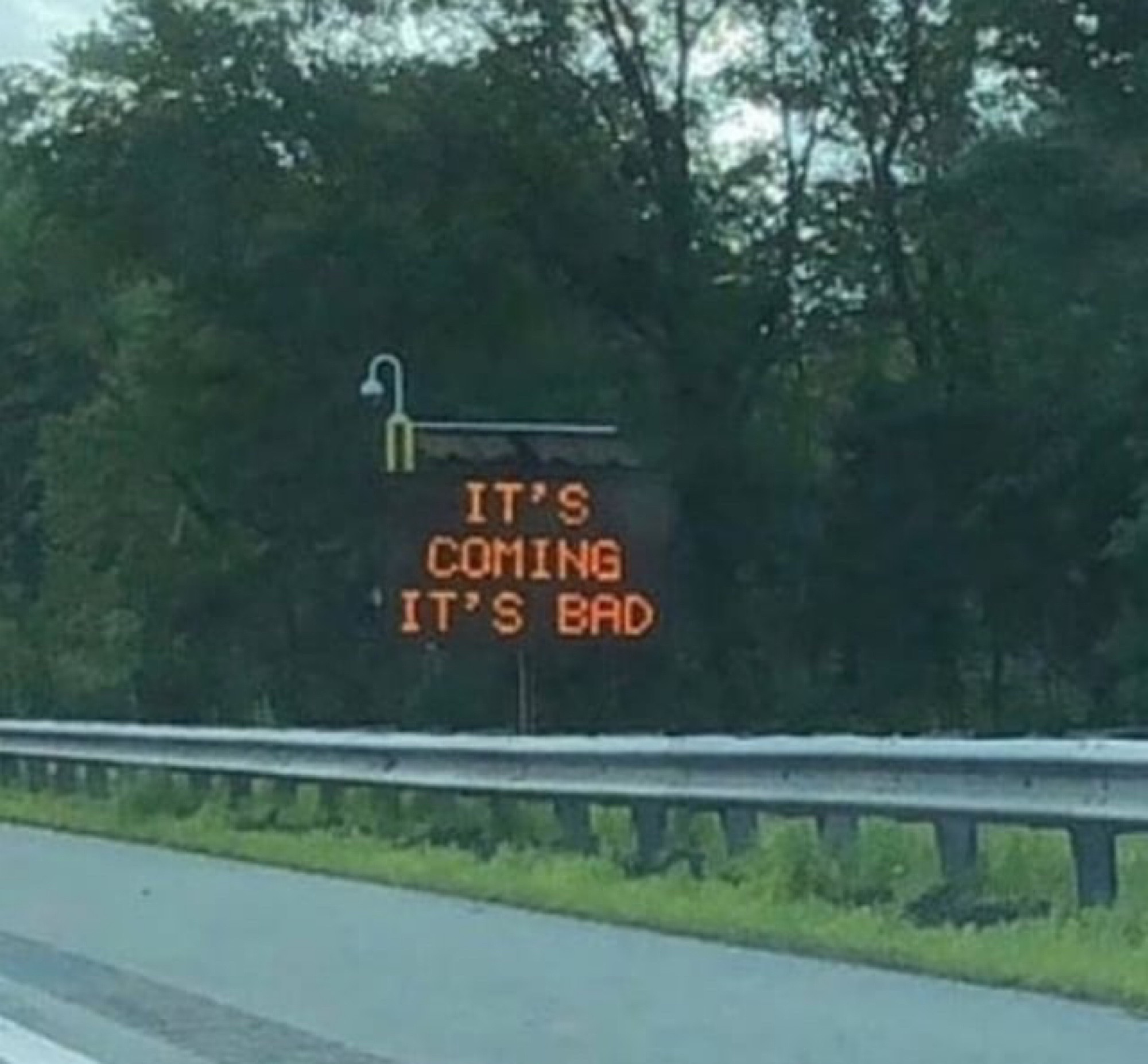 a roadside light-up traffic sign reading “IT’S COMING IT’S BAD”