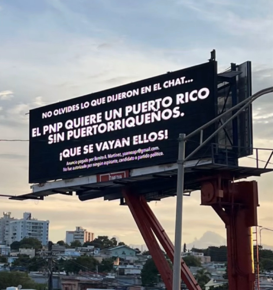 Outdoor na cidade de Porto Rico com o fundo preto e o texto em tradução livre “nao se esqueça o que disseram no chat… O PNP quer um Porto Rico sem Porto-riquenhos. Eles que se vão.” Na nota de rodapé o texto “anúncio pago por Benito A Martinez. Não foi autorizado por nenhum aspirante, candidato ou partido político”. A nota foi inserida após tentativa do partido de retirar as placas alegando se tratar de campanha da oposição