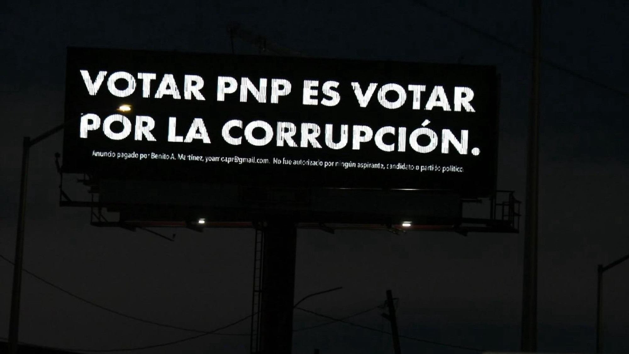 Outdoor na cidade de Porto Rico com o fundo preto e o texto em tradução livre “votar por pnp é votar pela corrupção” Na nota de rodapé o texto “anúncio pago por Benito A Martinez. Não foi autorizado por nenhum aspirante, candidato ou partido político”. A nota foi inserida após tentativa do partido de retirar as placas alegando se tratar de campanha da oposição