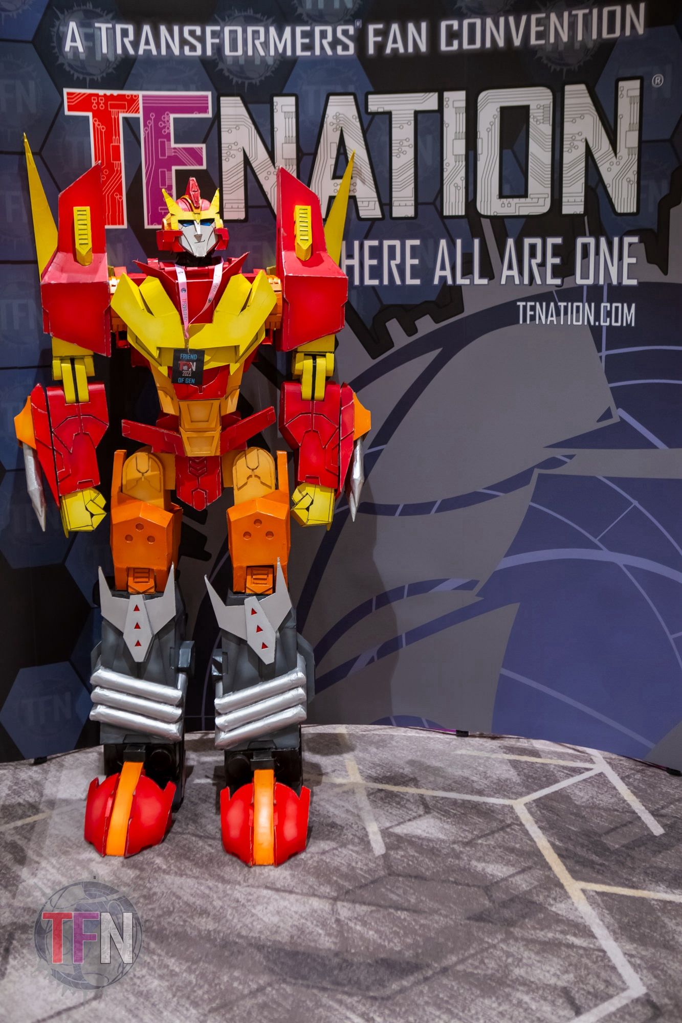 A 5 feet tall MTMTE Rodimus statue stands ready for photo-shots in-front of a TFNation banner.