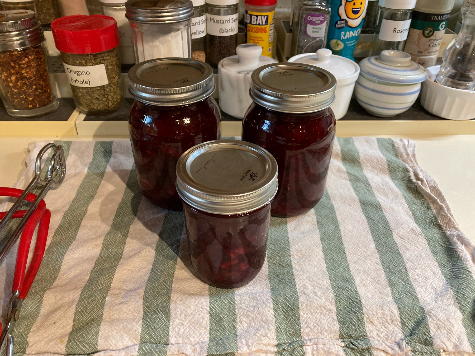 Jars of plum chutney cooling on a towel on the counter