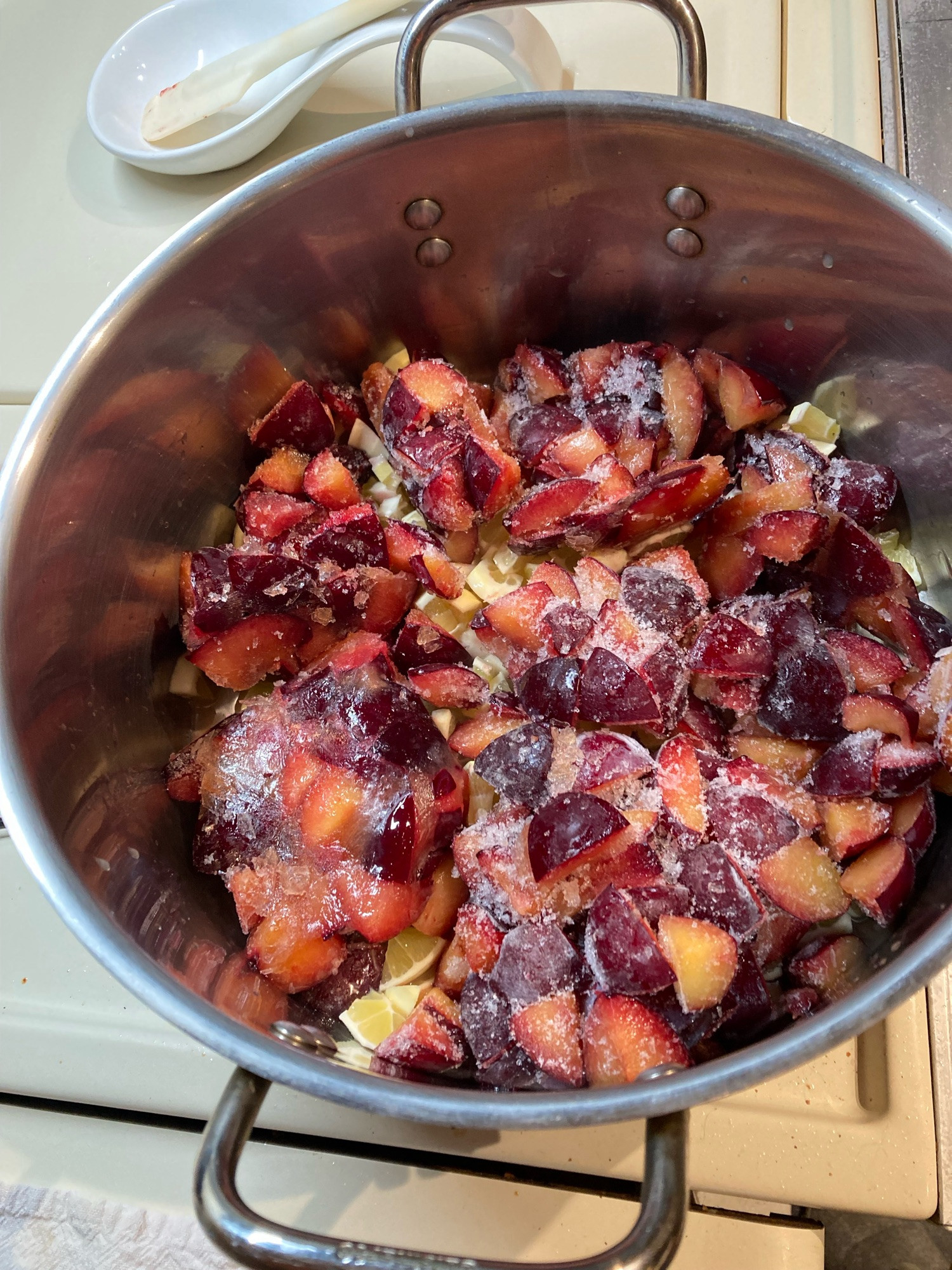 Frozen plum pieces and fresh lemon pieces in a pot