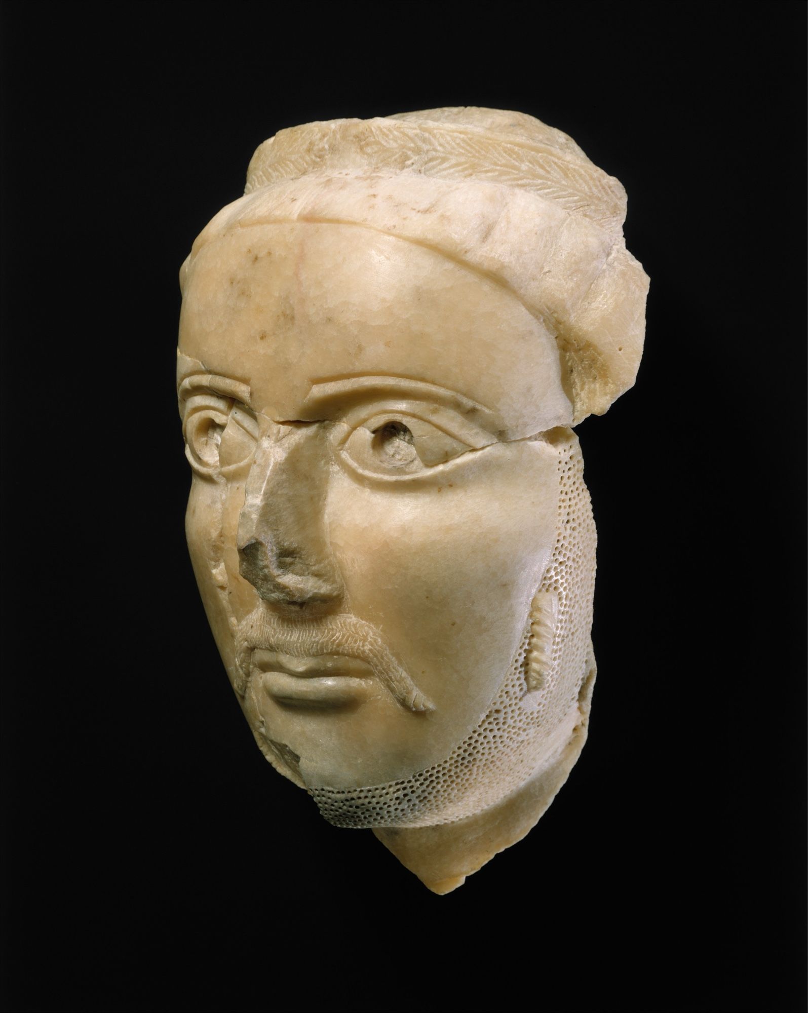 Head of a man
ca. 3rd–4th century CE
 Not on view

This fine male portrait head is thought to date from the middle of the first millennium A.D. and may have been part of a larger royal sculpture. The figure is wearing a stylized laurel wreath, a symbol of high rank. The use of the wreath to denote status reflects the influence of the Graeco-Roman world and appears in more realistic form on the coins of the kingdom of Himyar from the first centuries B.C. and A.D. A long mustache drapes along each side of the mouth, the chin is bearded, and a single ringlet is carefully carved on the surface of the left cheek. This last detail is undoubtedly significant since it is, to this day, characteristic of the hairstyle of Yemeni Jews. In the fourth century A.D. many of the kings of Himyar were converted to Judaism, so this feature may eventually aid in the identification of the figure. Carved from translucent alabaster with beautifully polished surfaces, … via the Met