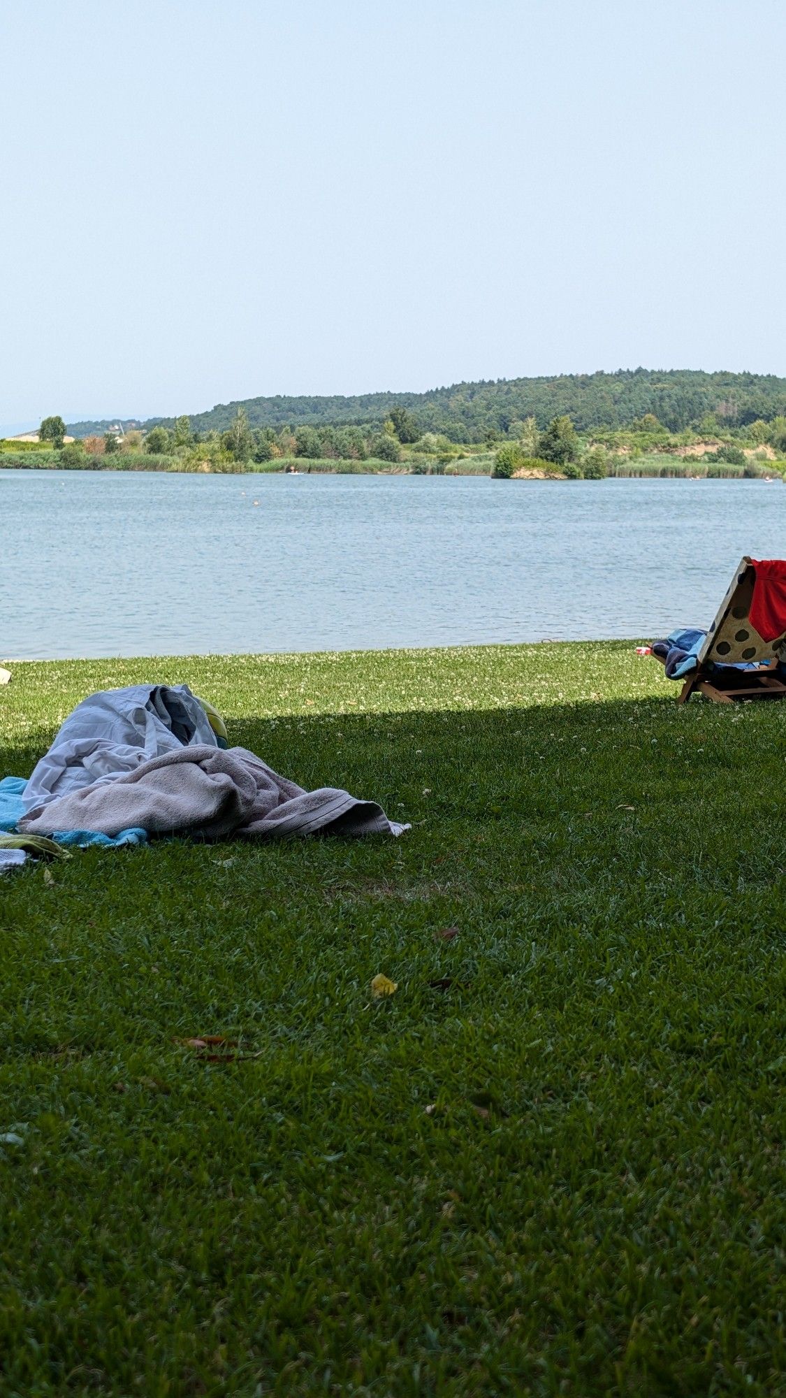 Wiese, Handtücher, Liegestuhl, Blick aufs Wasser mit Insel