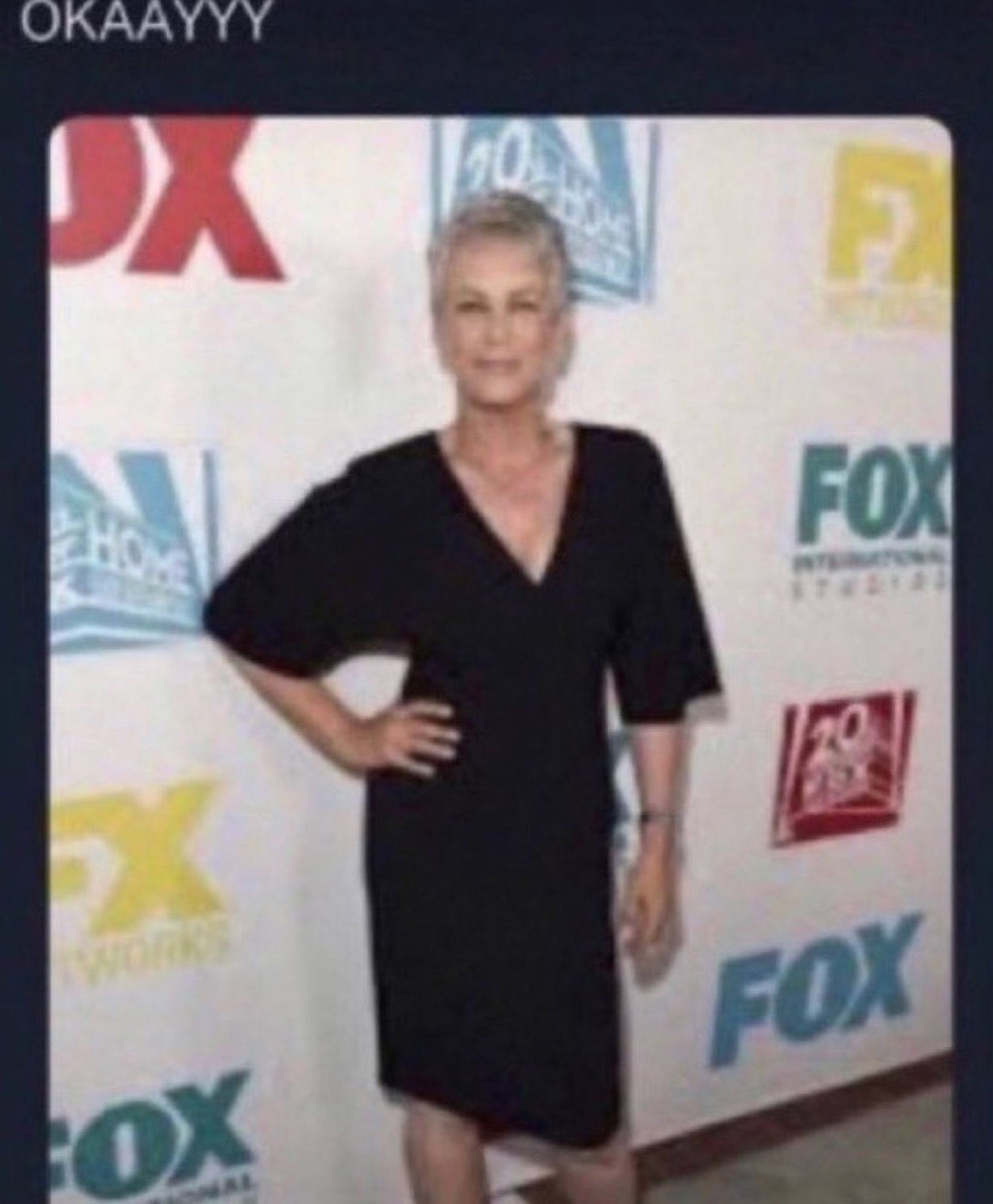 low-res image of Jamie Lee Curtis in a black dress, hand on hip. captioned "OKAAYYY"