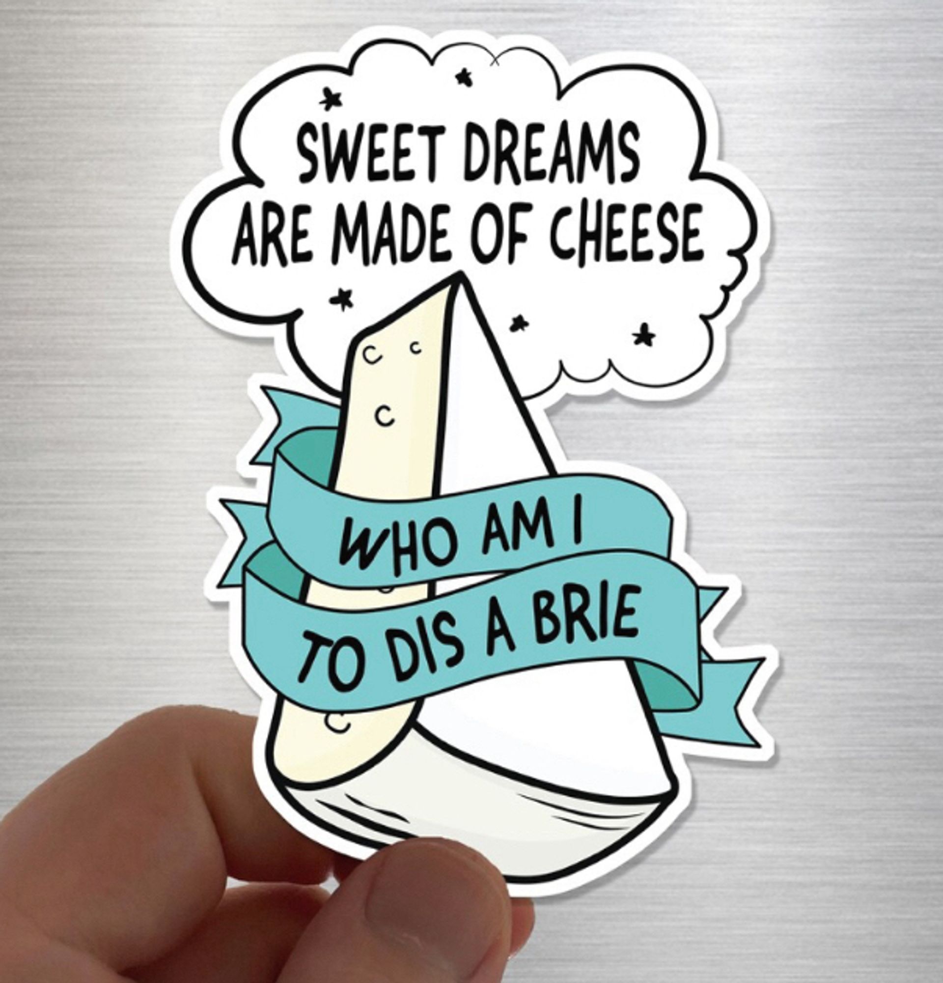 Sticker von Etsy. 
In einer comic Wolke steht: Sweet dreams are made of cheese. 
In einem Stück Camembert mit türkisem Spruchband steht: who am I to dis a Brie