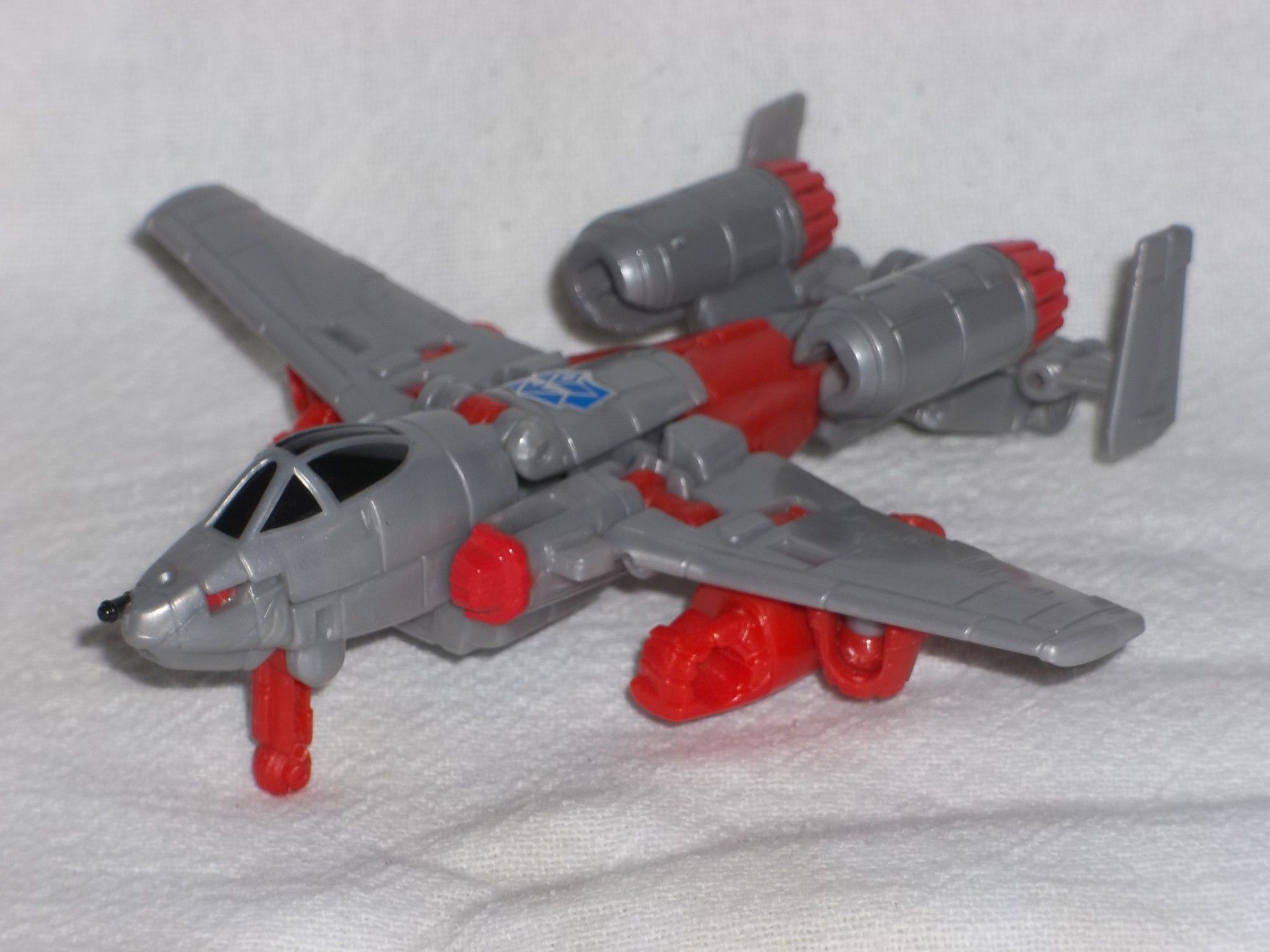 A Transformers Combiner Wars G2 Style Powerglide action figure, in vehicle mode, with a custom blue G2 Decepticon symbol on its back.