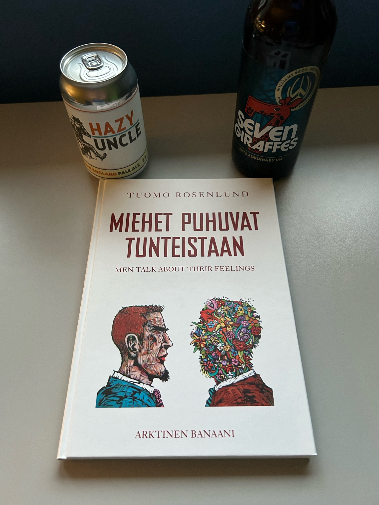 Kirja ”Miehet puhuvat tunteistaan” sekä olutpullo ja -tölkki