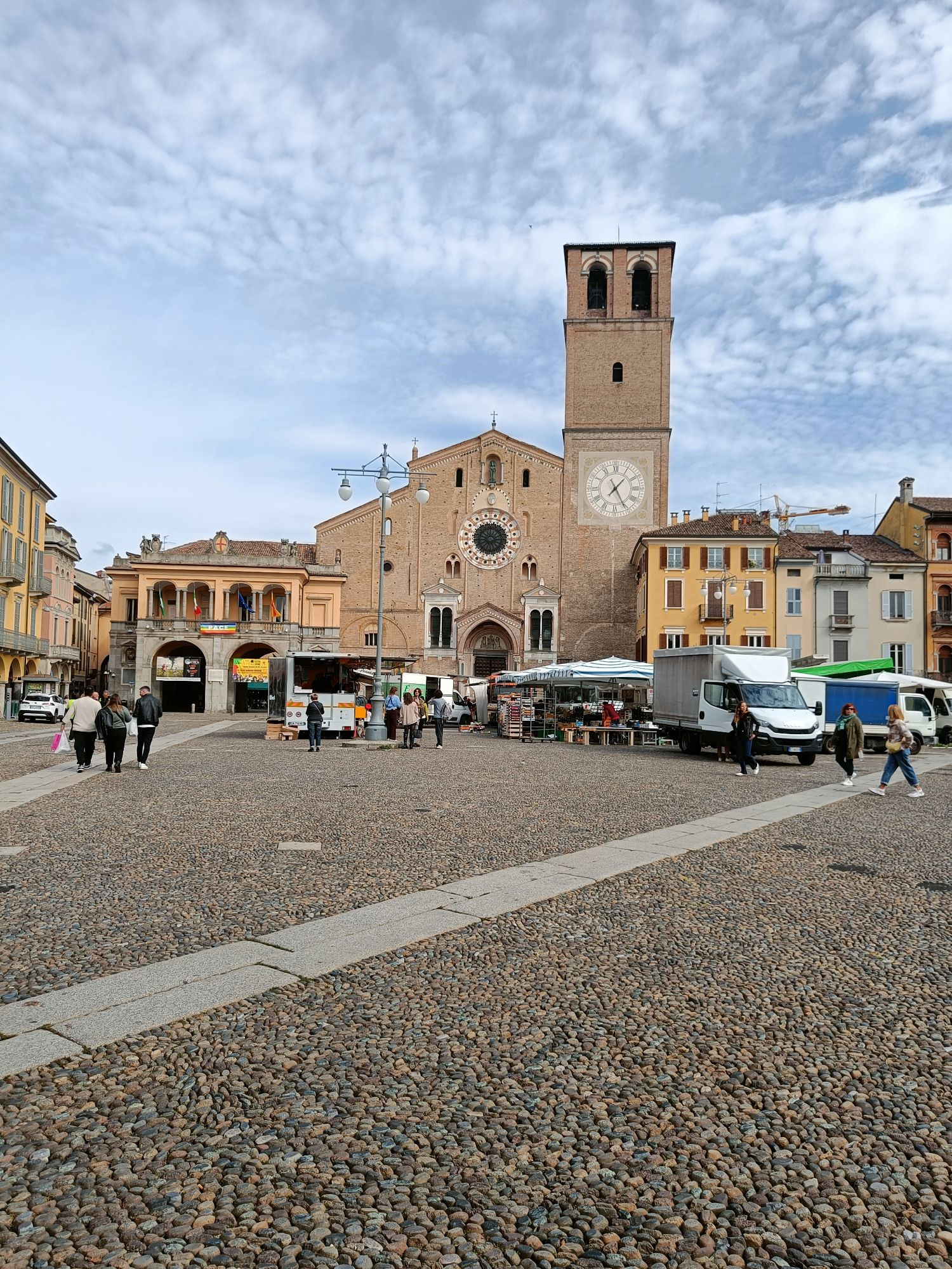 Una foto della facciata principale del duomo di Lodi, La basilica cattedrale della Vergine Assunta, dalla piazza. Sono presenti anche alcuni stand del mercato settimanale 