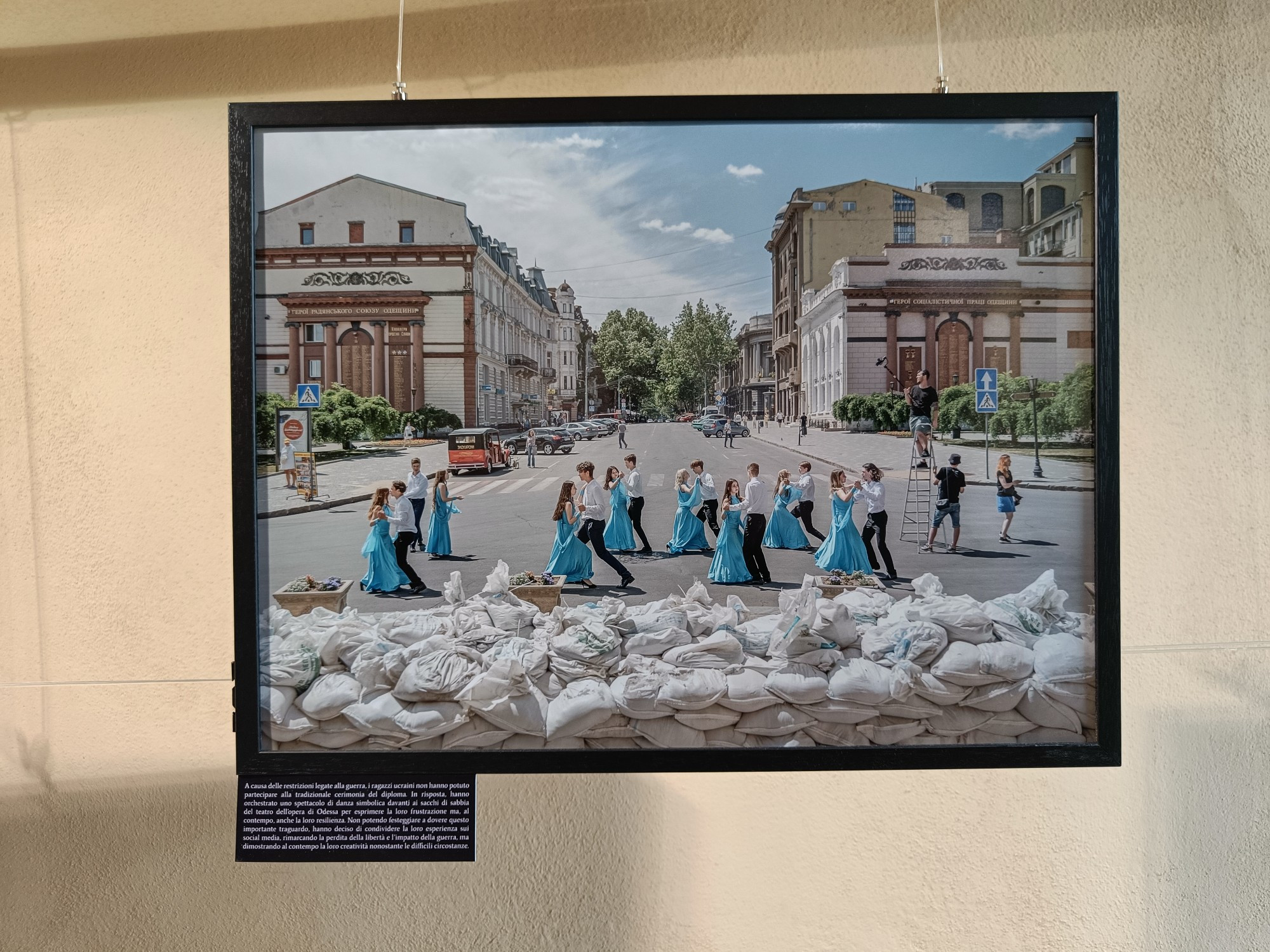 Una delle foto del festival, che ritrae studenti e studentesse ucraine che ballano il giorno del loro diploma, davanti ai sacchi di sabbia posizionati per proteggere il teatro di Odessa.