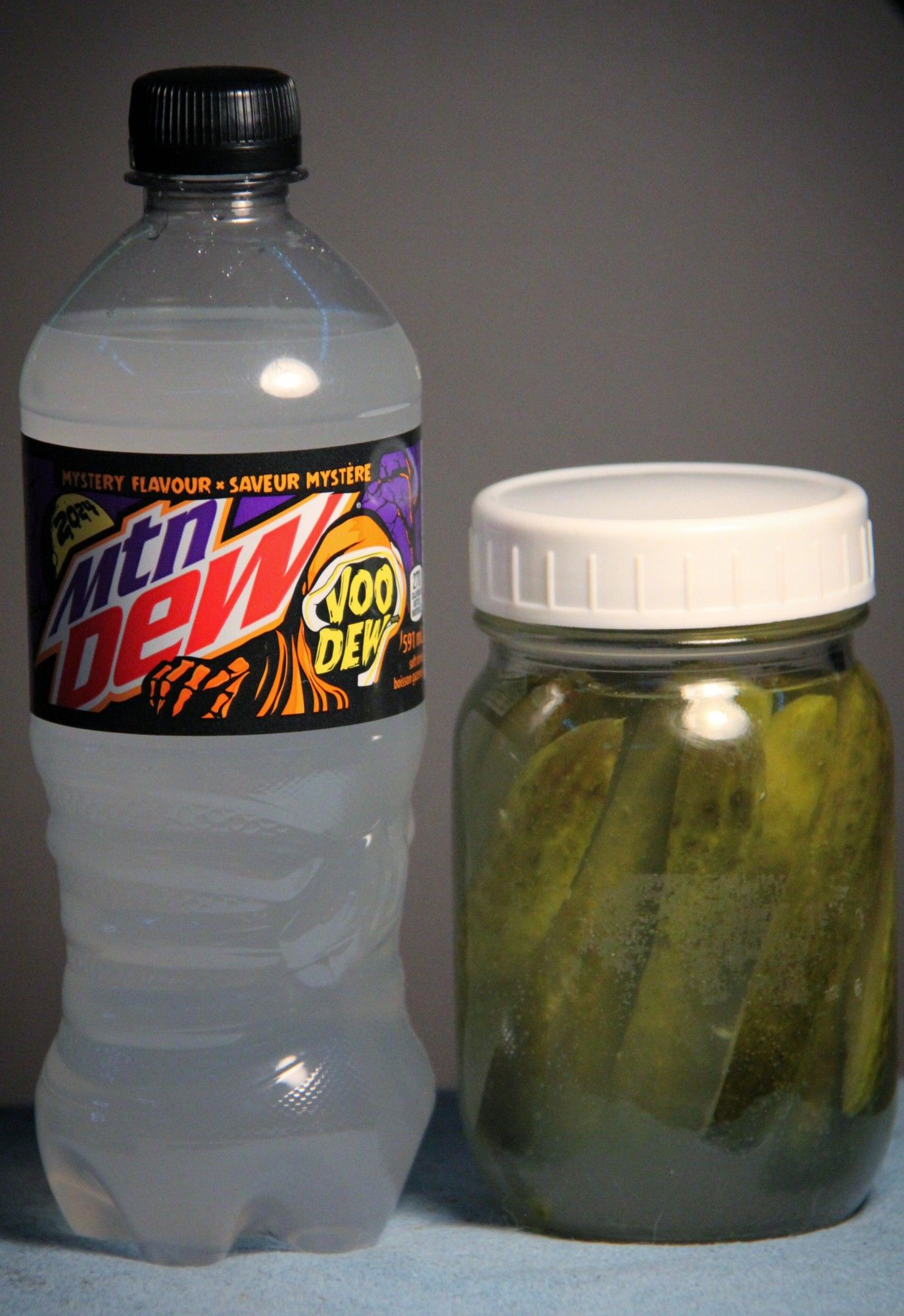 Picture.
A bottle of voodew soda stands next to a jar tht has also been filled with the soda. Pickles are floating in the jar, steeping in the soda.