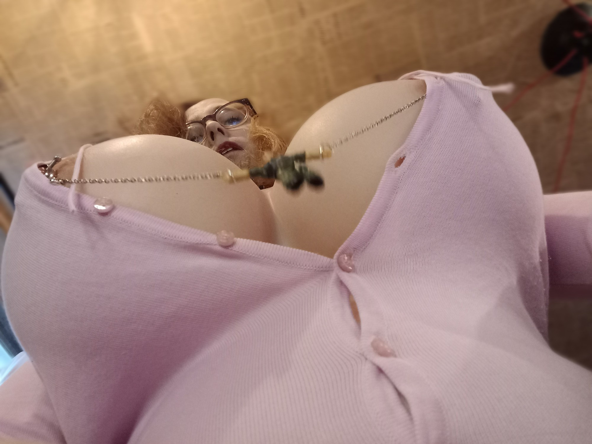 Low angle POV of DiDi Star. A tiny person is strung up by the wrists, shackled to nipple clamps hidden under her top.