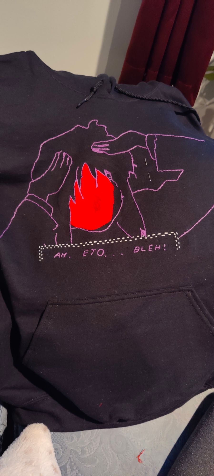 Embroidered piece on a black hoodie featuring fanart of the character Amy from the videogame Faith the unholy Trinity doing the "ah eto... bleh" meme