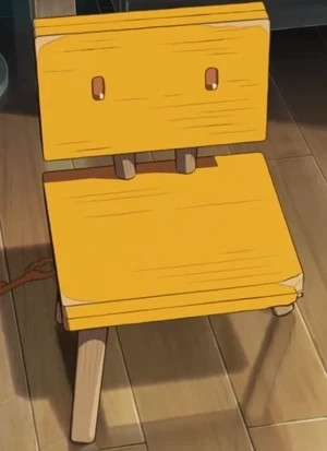 Yellow chair with 3 legs. Has some damage. The chair back has eyes.