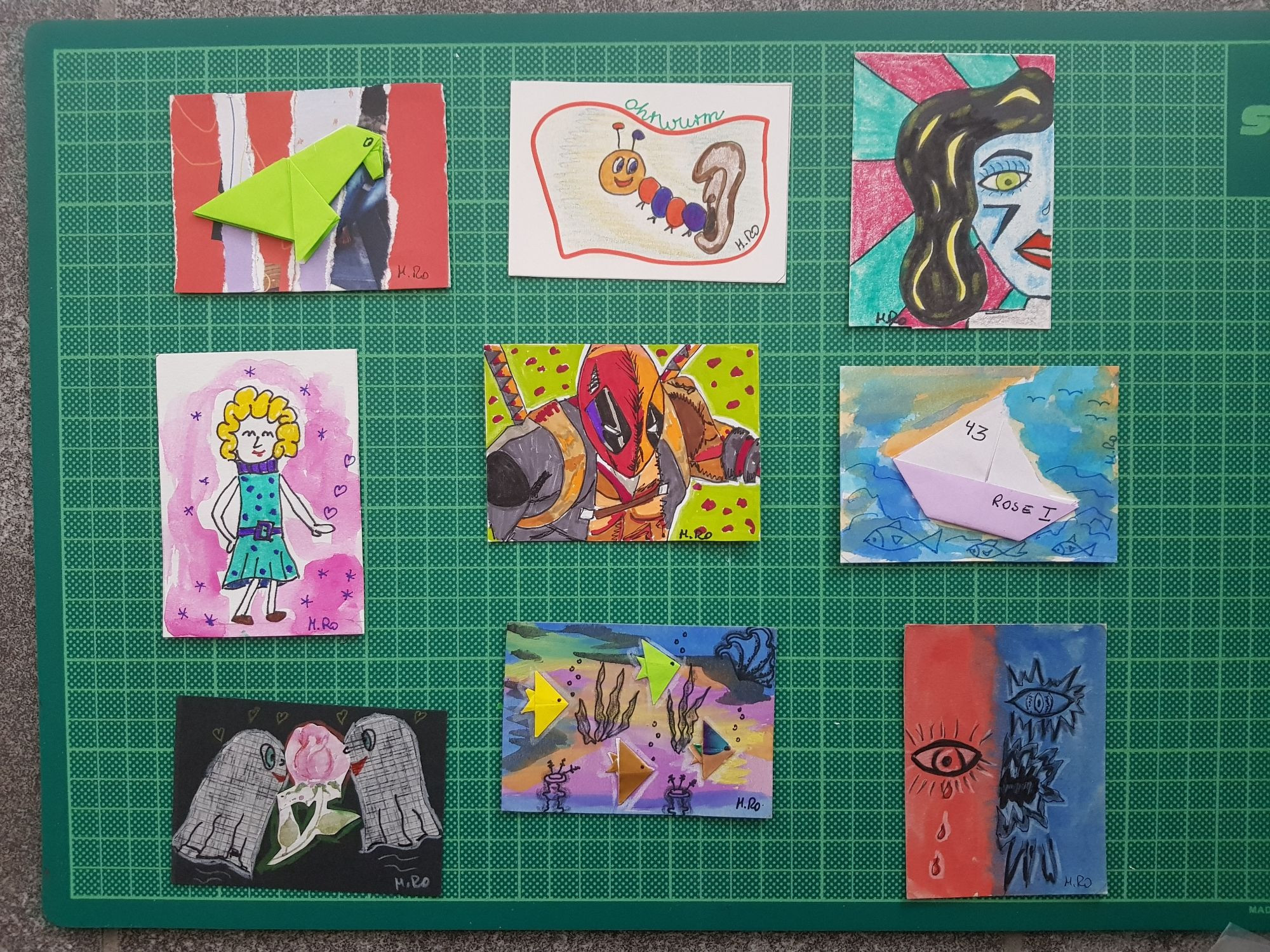 9 ATC Karten
Obere Reihe links: grüner Origamivogem auf rot-weissem Hintergrund. Mitte: Ohrwurm (Ein Ohr und ein Wurm). Rechts: Abstraktes Gesicht, Frau. Blaue Farbe.
Mitte links: tanzende blonde Dame in Türkiskleid vor pinkem Hintergrund. Mitte: Deadpool. Rechts: Origamischiff auf blauem Hintergrund.
Unten links: 2 Geister und in der Mitte eine pinke Rose auf schwarzem Hintergrund. Mitte: Origami-Fische auf Meeresgrund. Rechts: Dark ATC-Karte mit Augen auf rotem und blauem Hintergrund