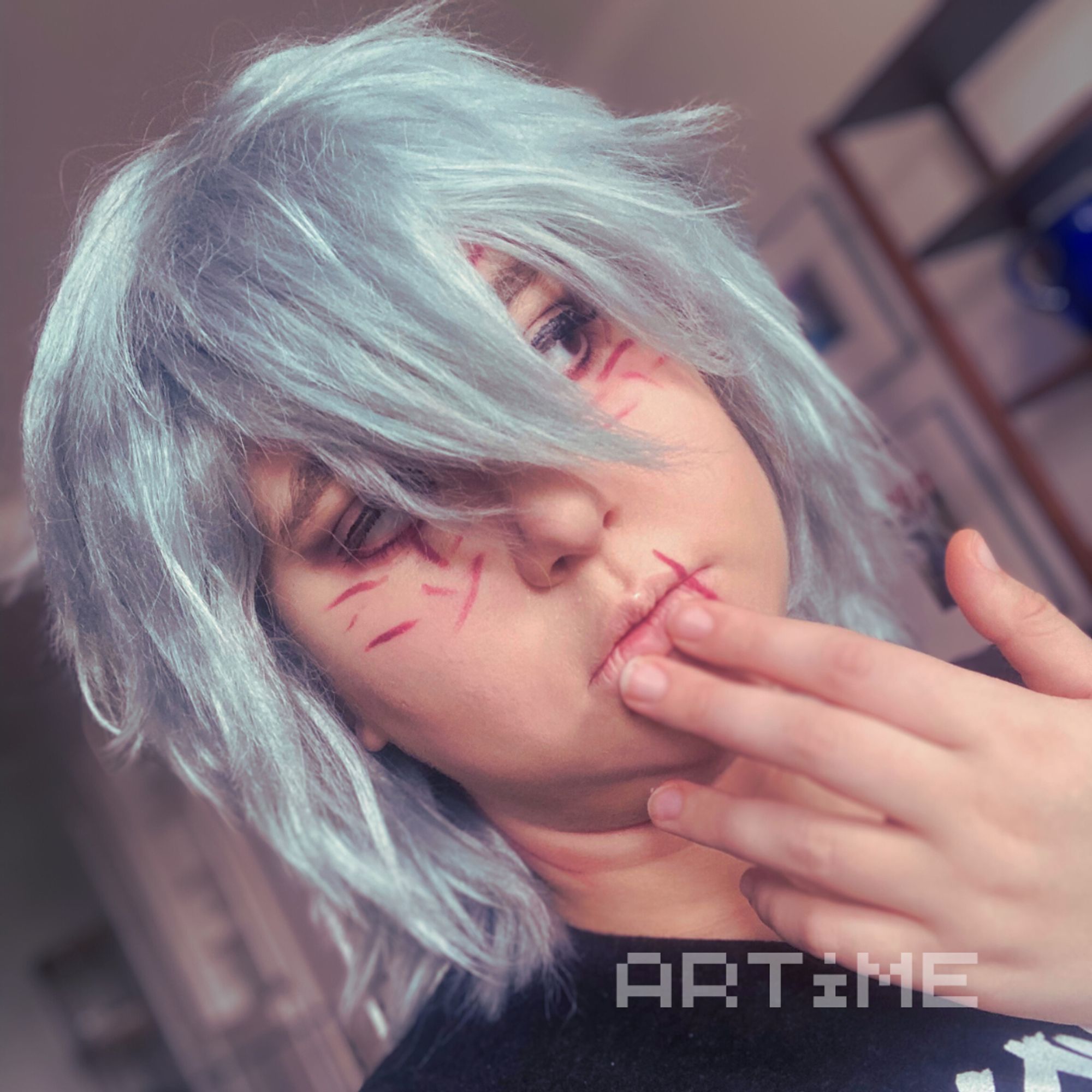 A Tomura Shigaraki cosplayer with his hand to his face and eyes open and looking to the side.