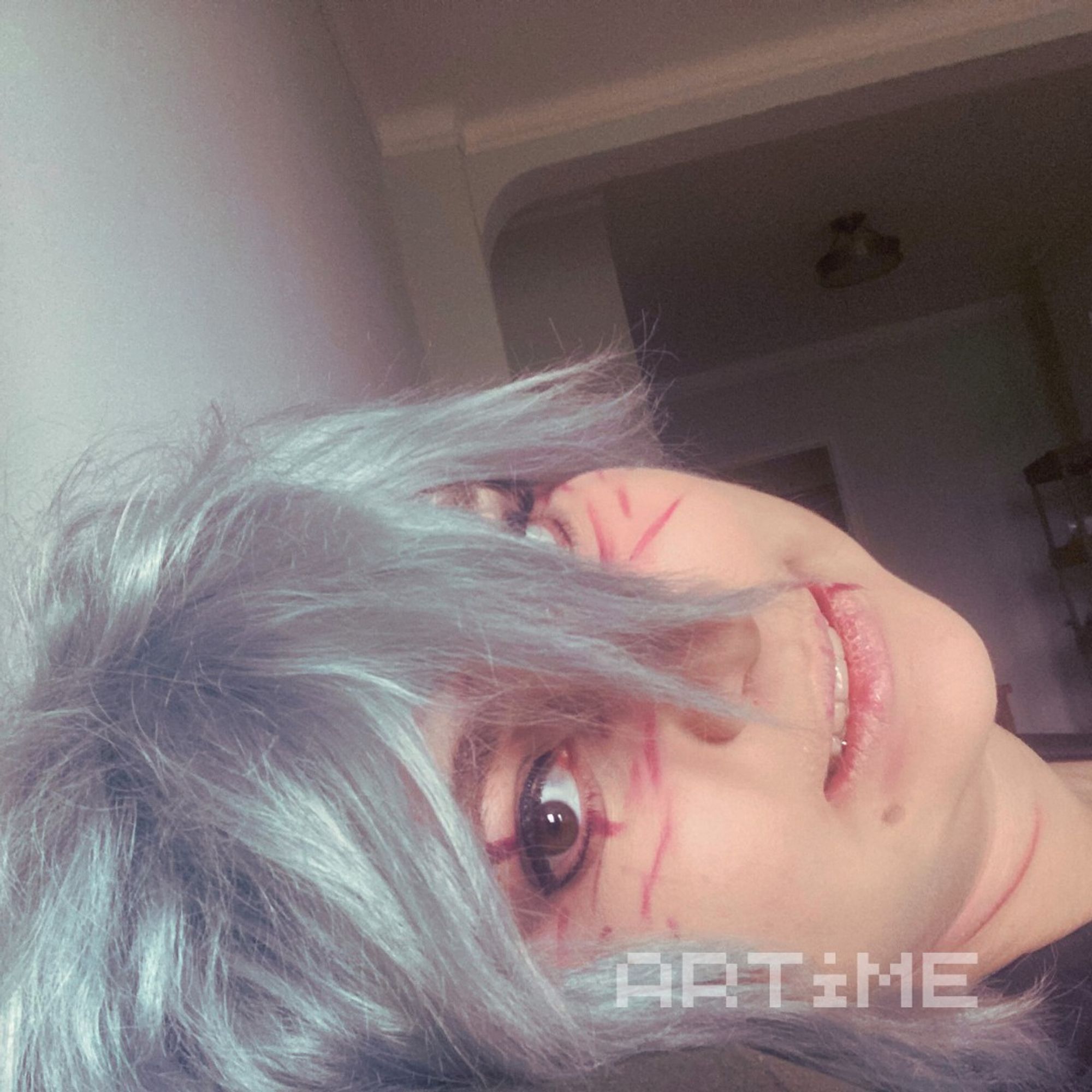 A Tomura Shigaraki cosplayer sideways and grinning at the camera