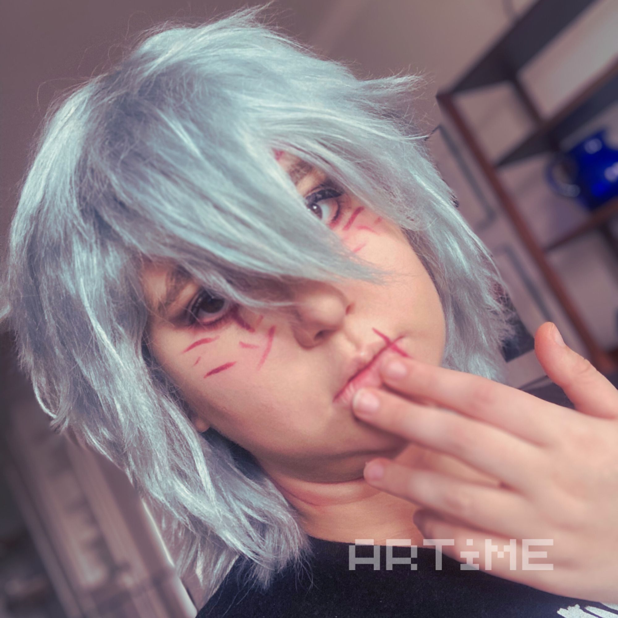 A Tomura Shigaraki cosplayer with his hand to his face and eyes open and looking forward.