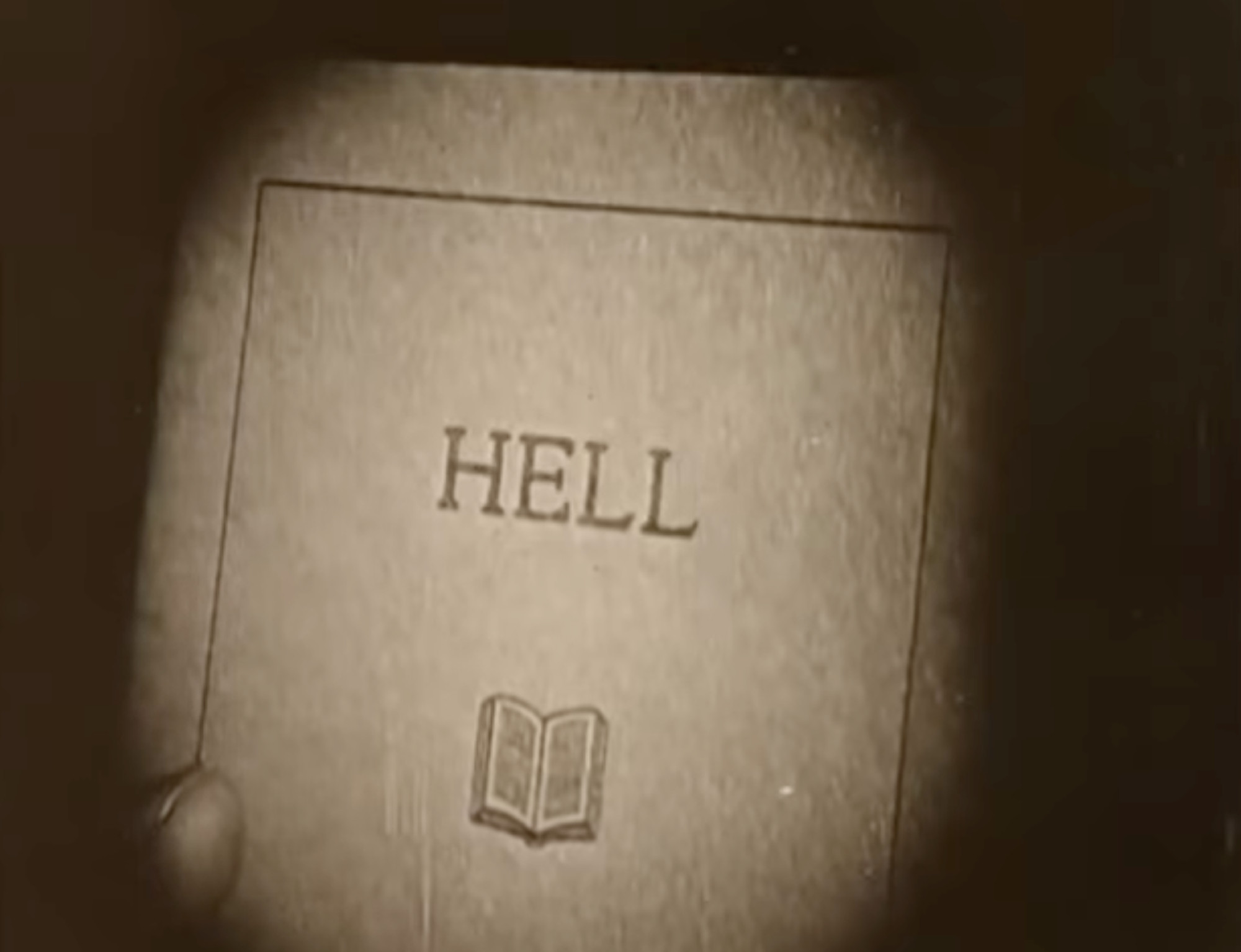 Filmstill showing the close-up of a book cover saying HELL