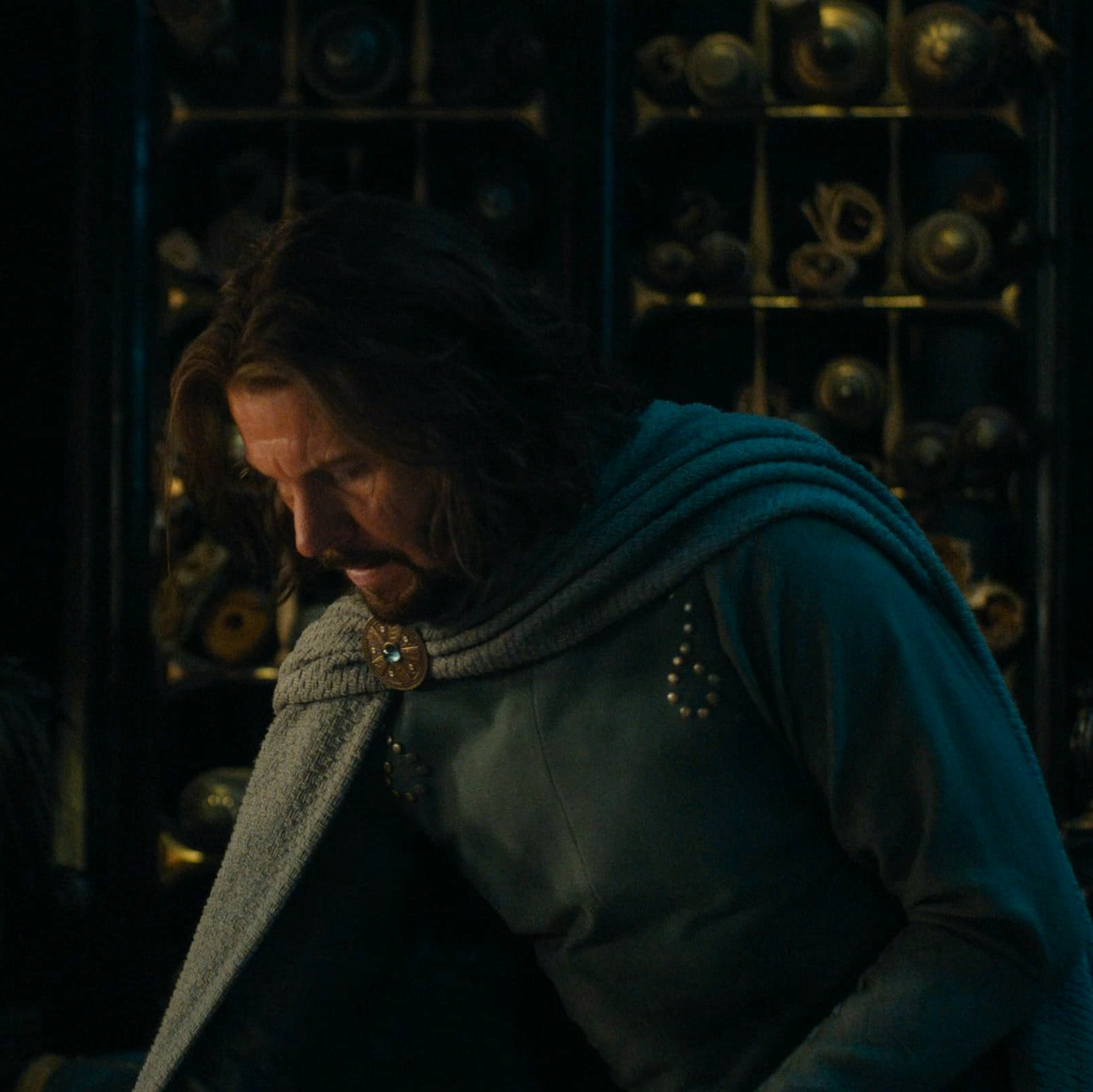 a screenshot of lloyd owen as elendil in the rings of power season 2 episode 8. he's looking down at something out of view in the scene where he was trying to convince míriel to escape with him