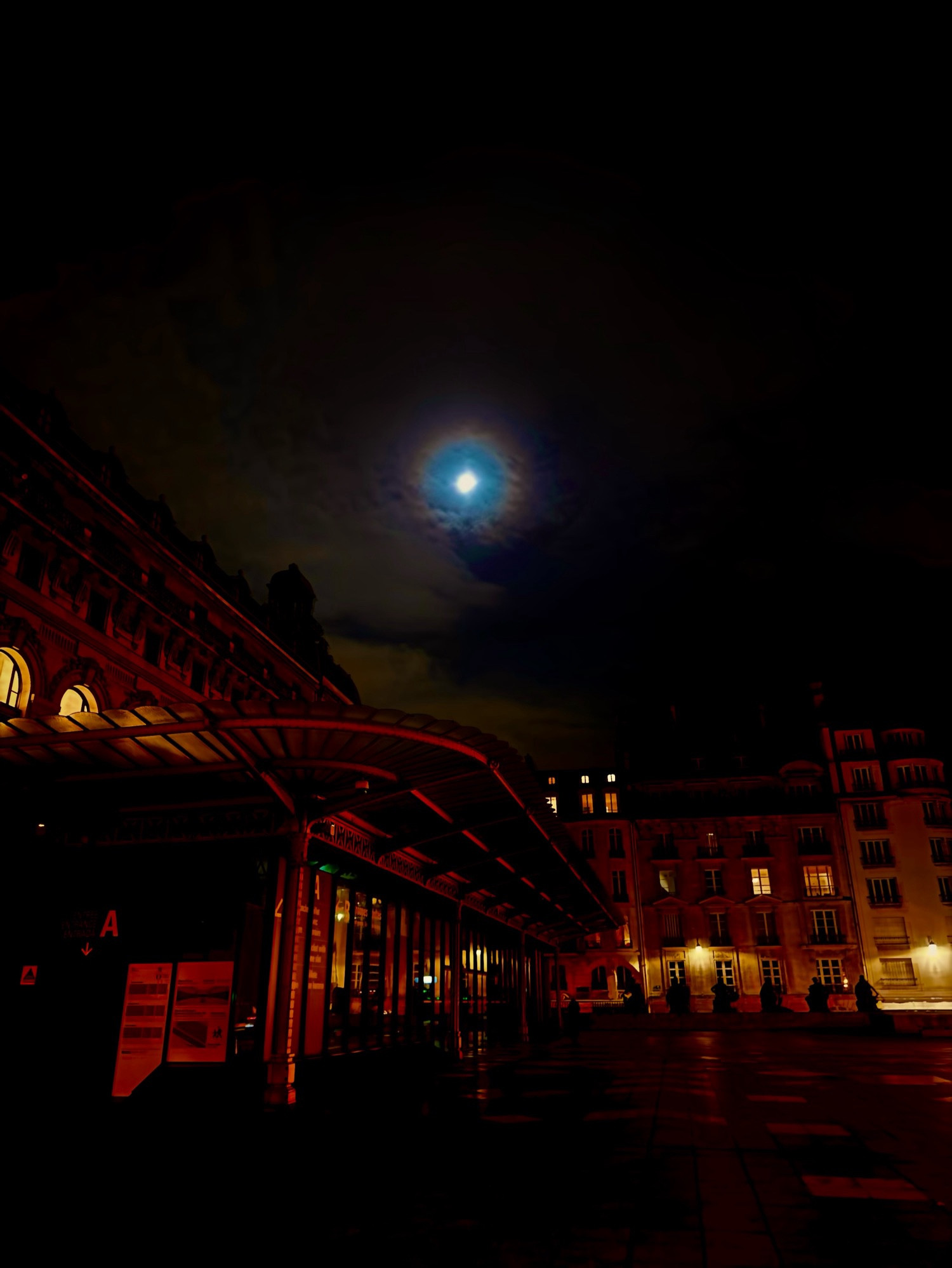 A full moon chromatically shining on to a very red and auburn tinted Parisian square