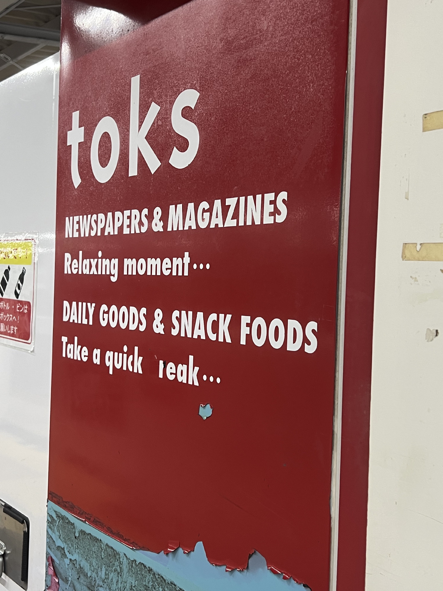 A sign in English in the wall of a little station shop saying “toks newspapers and magazines. Relating moment… daily goods and snack foods. Take a quick break” except that the “b” has peeled off and the “r” become a little deformed so that “break” looks like “leak”. 