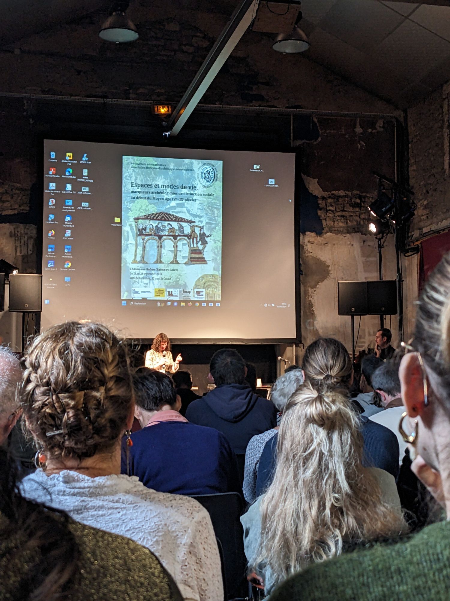 Vue d'une salle de conférence remplie de personne écoutant une conférencière parler