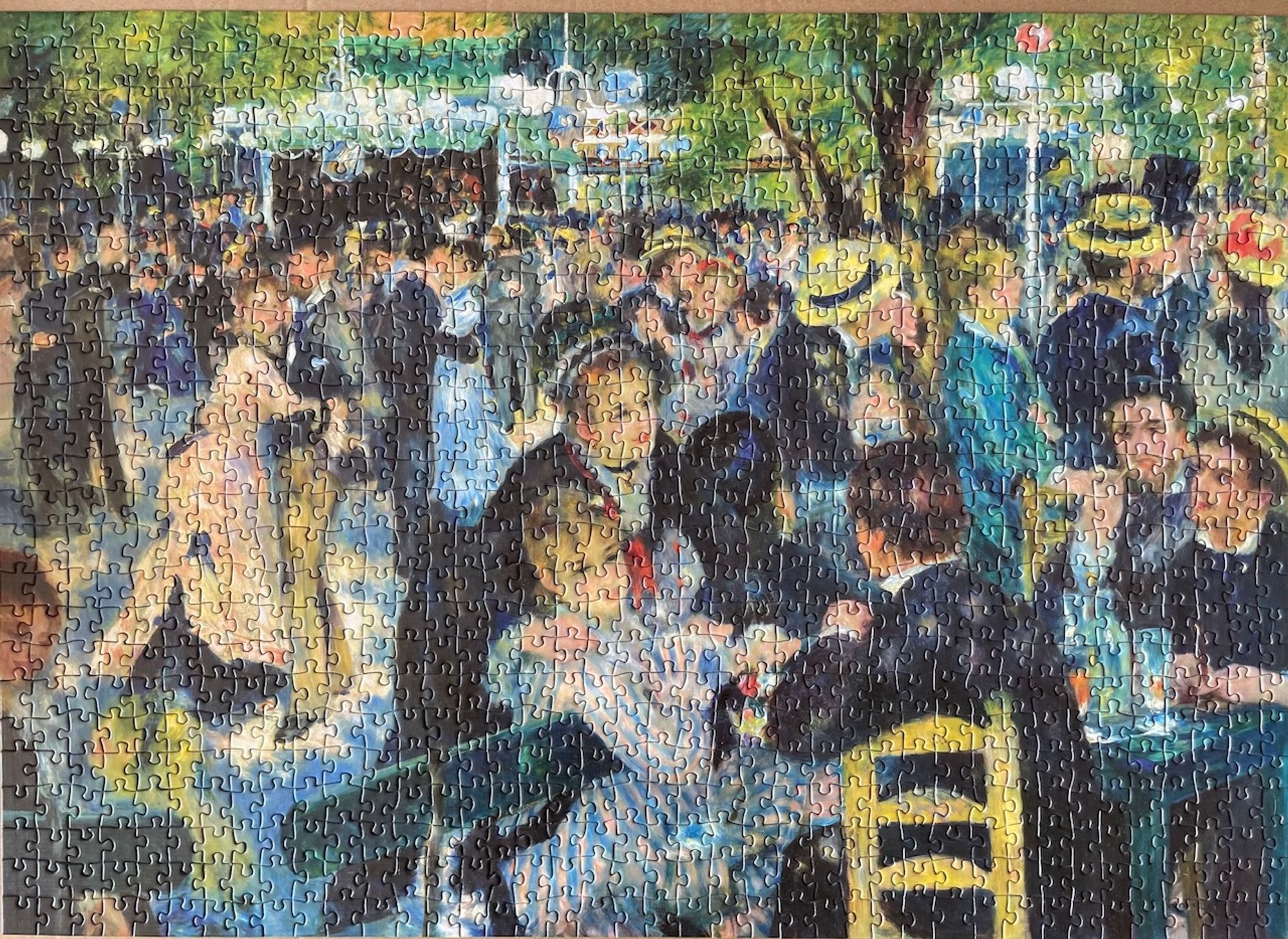 Completed 1000 piece jigsaw puzzle of Renoir's 1876 impressionist painting titled Dance at Le Moulin de Gallette

It depicts a bustling nineteenth Parisian scene of working class people dressed up in flowing dresses, suits, top hats and boater hats to dance in the streets in the leafy Montmartre district

In the foreground is a woman in a light blue and white striped dress with frilly lace cuffs sitting on a dark turquoise wooden bench, her bent arm leaning over it as she turns to face a suited gentleman with brown hair seated on a yellow wooden cross barred chair with his back to the viewer. A second woman in a dark dress and black and white lace headband and white lace collar is behind her, resting her hand on the seated woman's shoulder 

To the right are two dapper gentleman seated at a round dark turquoise table with drinks glasses and bottle on it

Various couples are dancing in the centre left and swathes of dancers, tall leafy trees and hanging glass bulbs fill the background