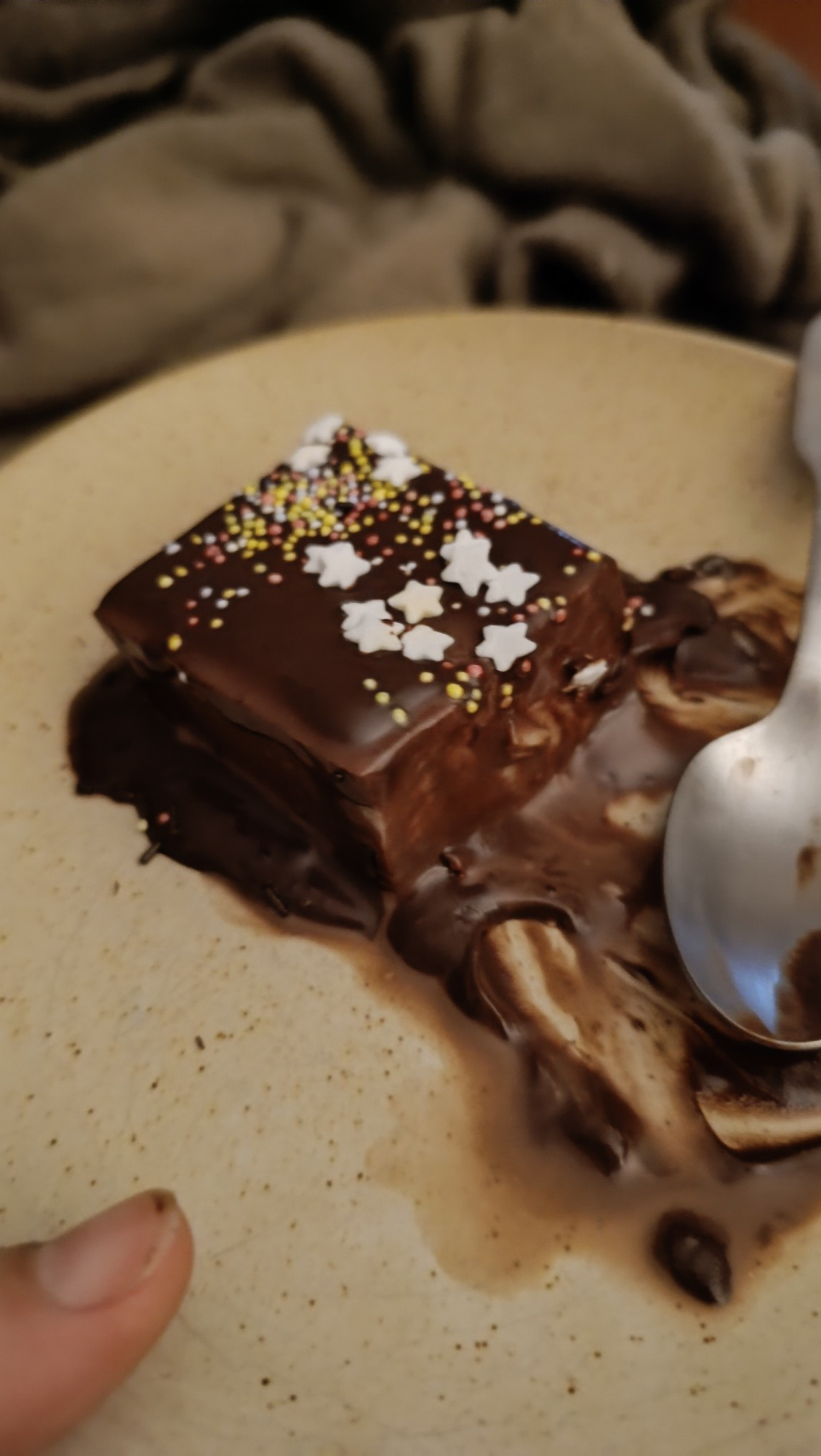 Flan au lait recouvert de chocolat fondu et de petites décorations : étoiles et billes de couleur.