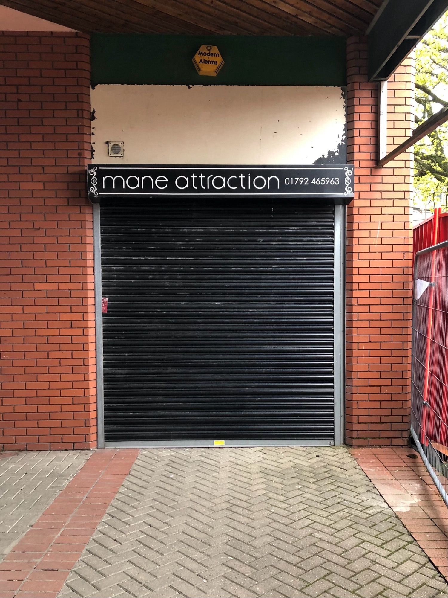 A closed-down shop in the red-brick open-air St. David’s Shopping Centre in Swansea. The sign says ‘Mane Attraction’.