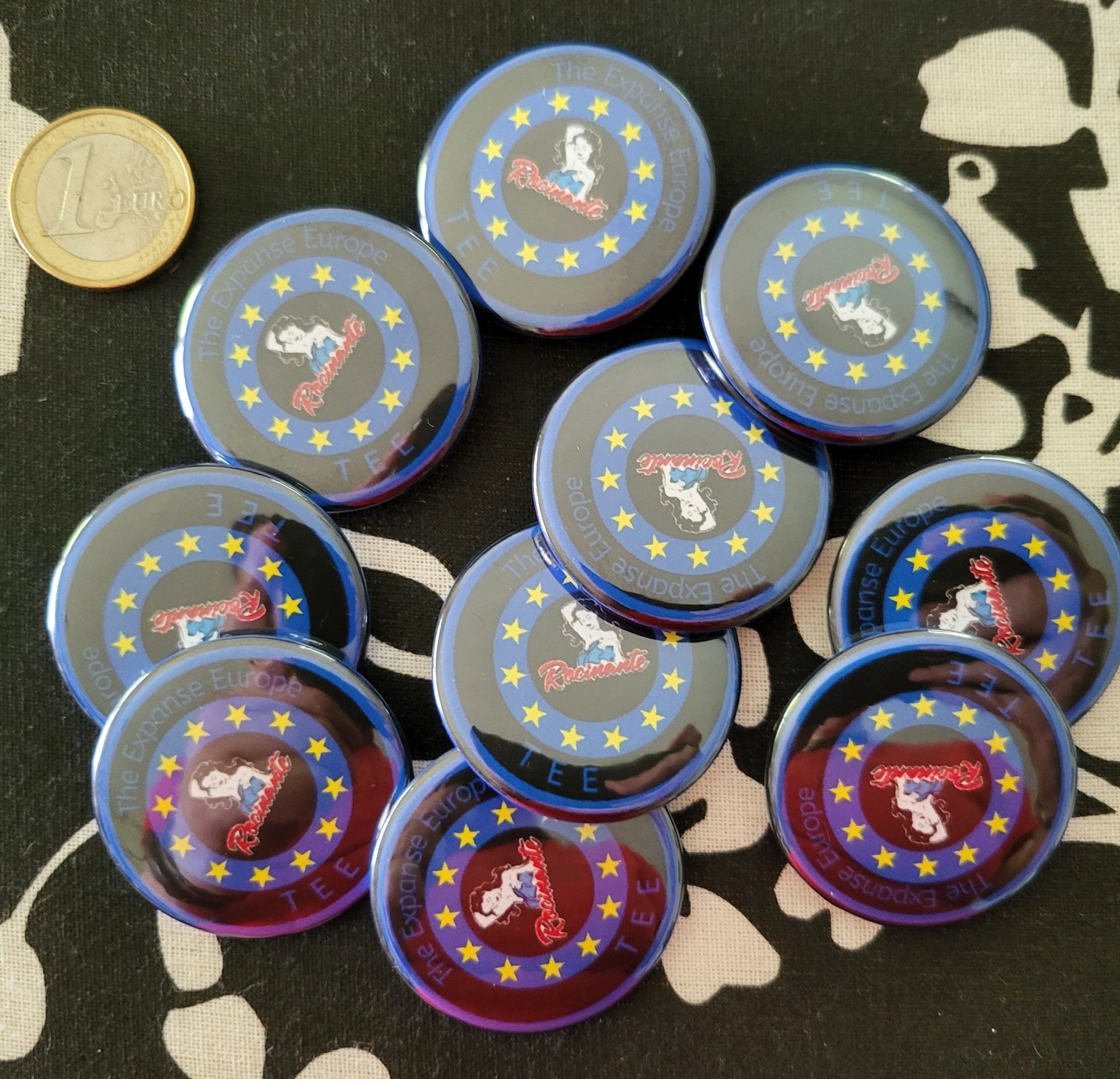 A bunch of buttons with Lady Rocinante in the middle, surrounded by yellow stars and the words "TEE The Expanse Europe" in blue letters.