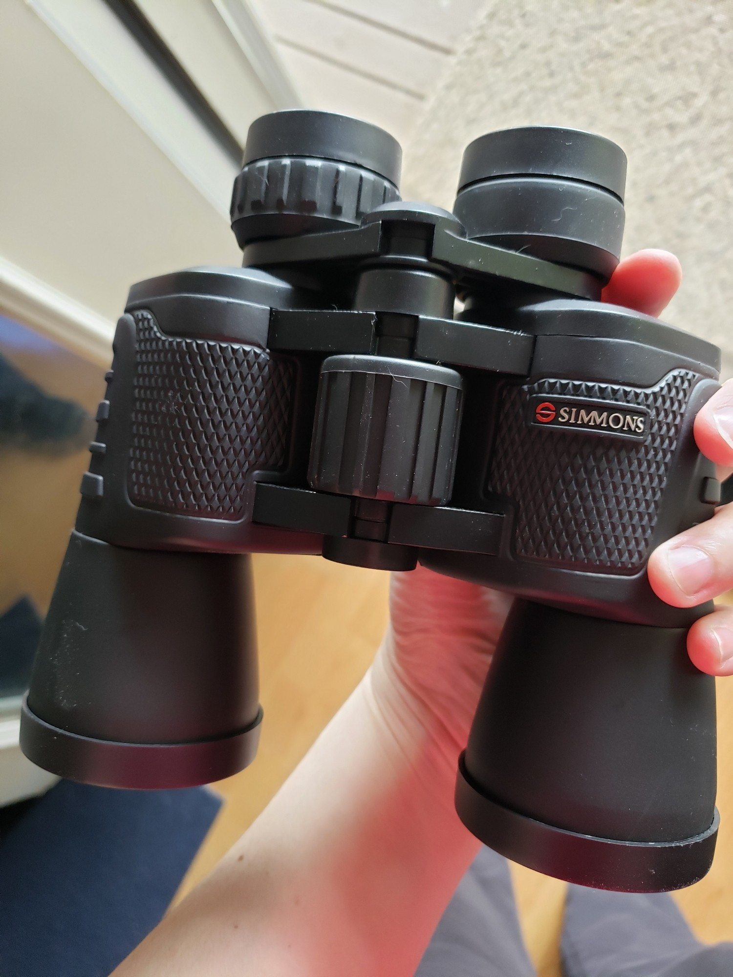 A hand holding Simmons black binoculars