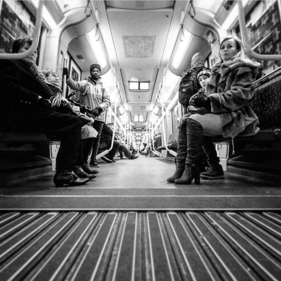 Low shot with camera on the floor from interior of Berlin subway (U-Bahn) with passengers sitting on both sides watching.