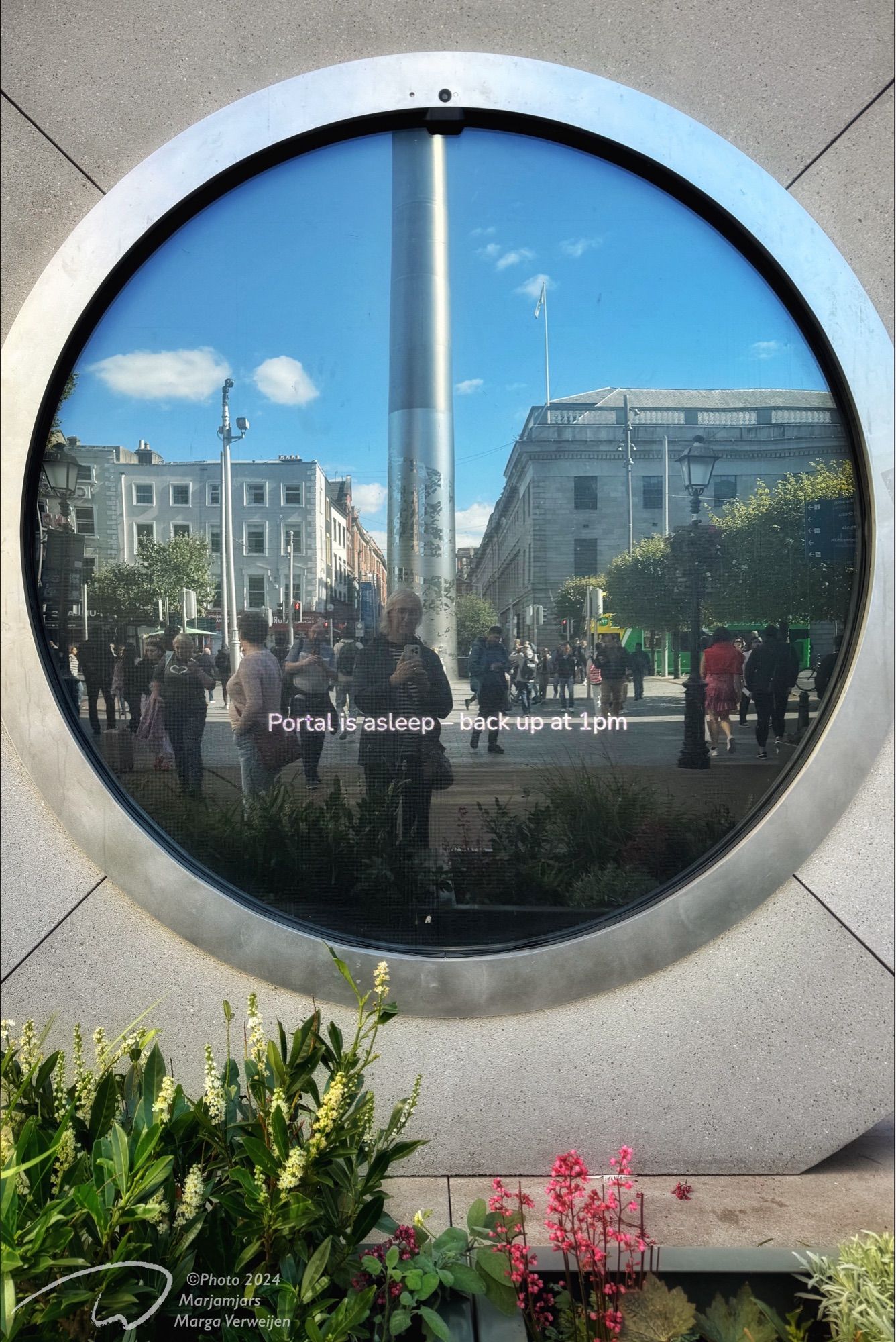 Screen of the circular portal (asleep) with reflection of its surroundings (The Spire on O’ Connell street) and me in Dublin city Centre.