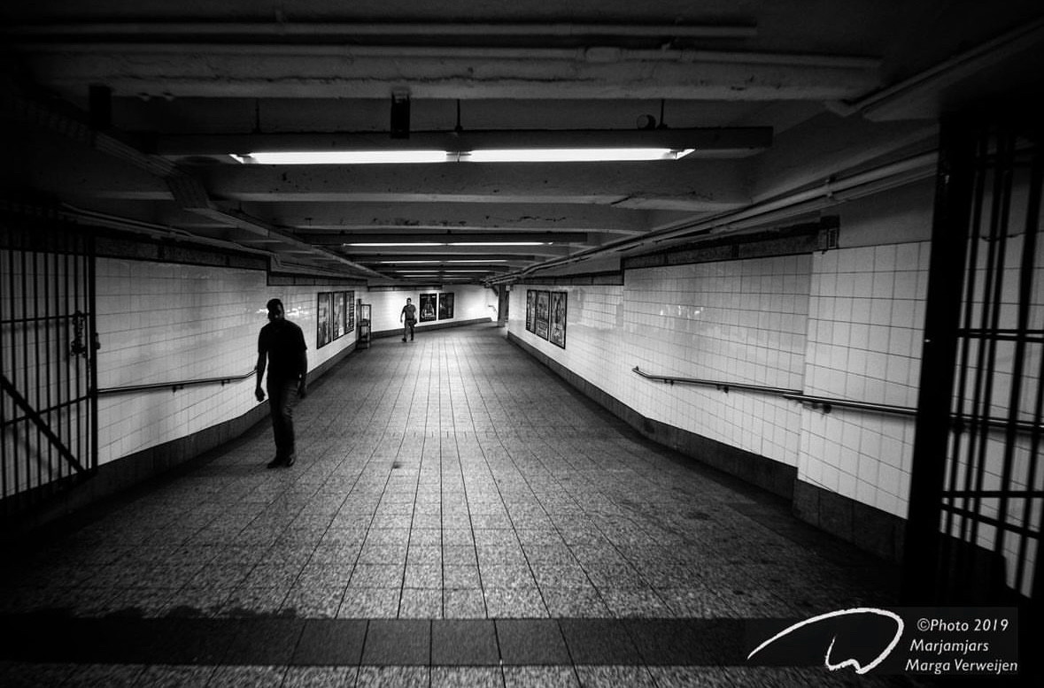 Dark, almost deserted underground passage of the New York subway with only two people walking towards me.