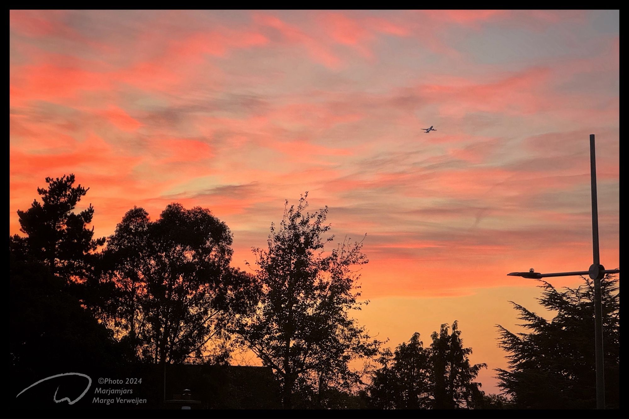 View on the evening light with an aeroplane crossing the red sky just after takeoff in Dublin.