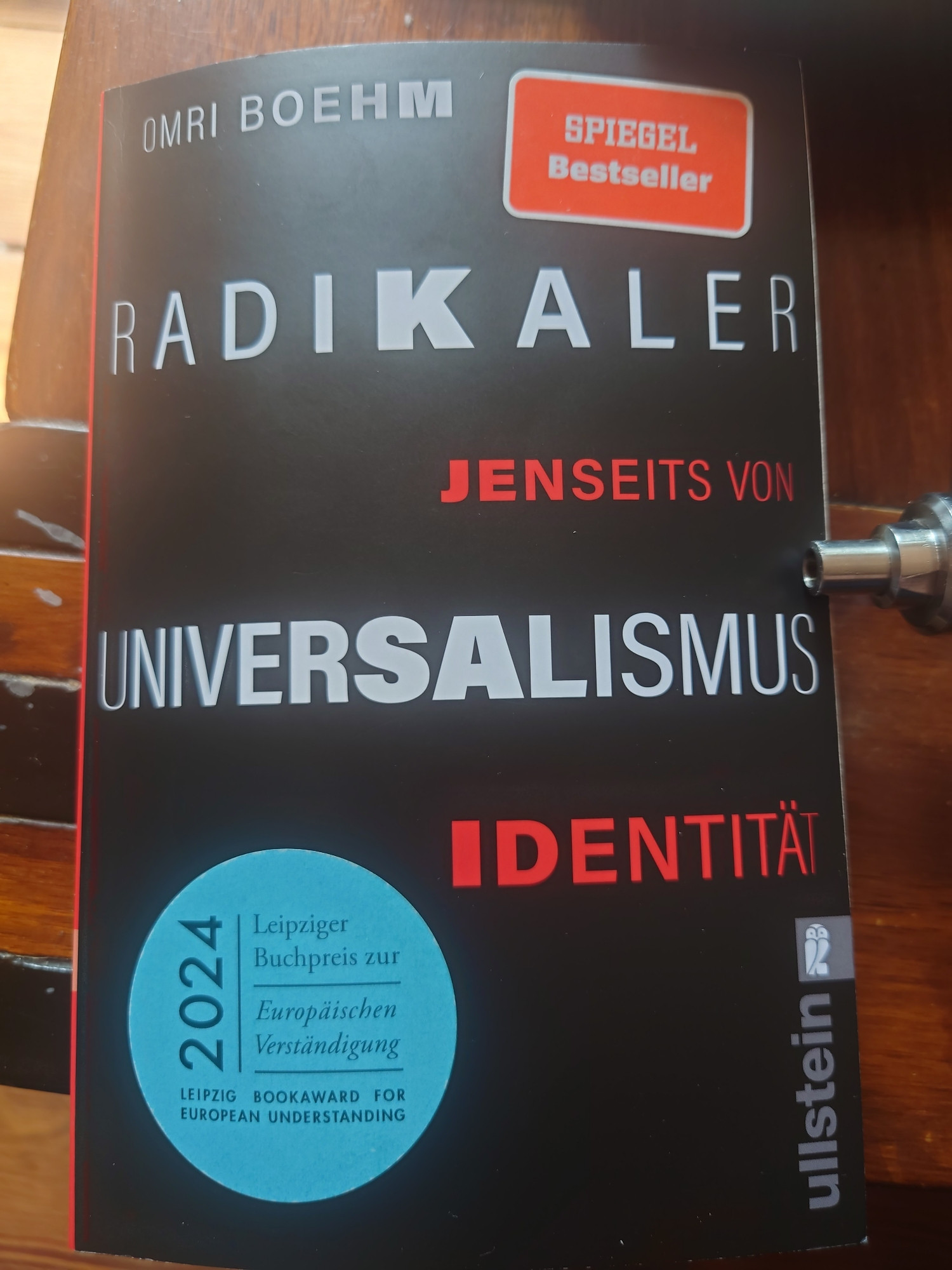 Foto: Auf einem Holztisch liegt ein Exemplar des Buches von Omri Boehm "Radikaler Universalismus - Jenseits von Identität"