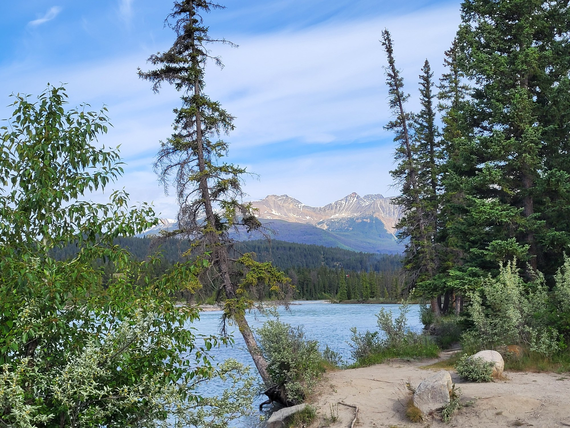 River, green trees rocks, and mountains. 